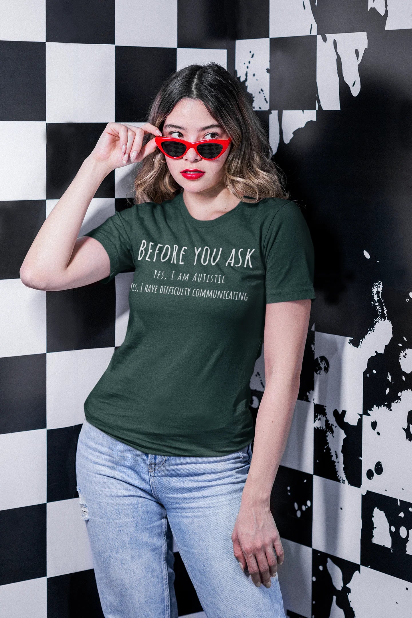 Woman wearing a green t-shirt with text, standing against a black and white checkered wall.