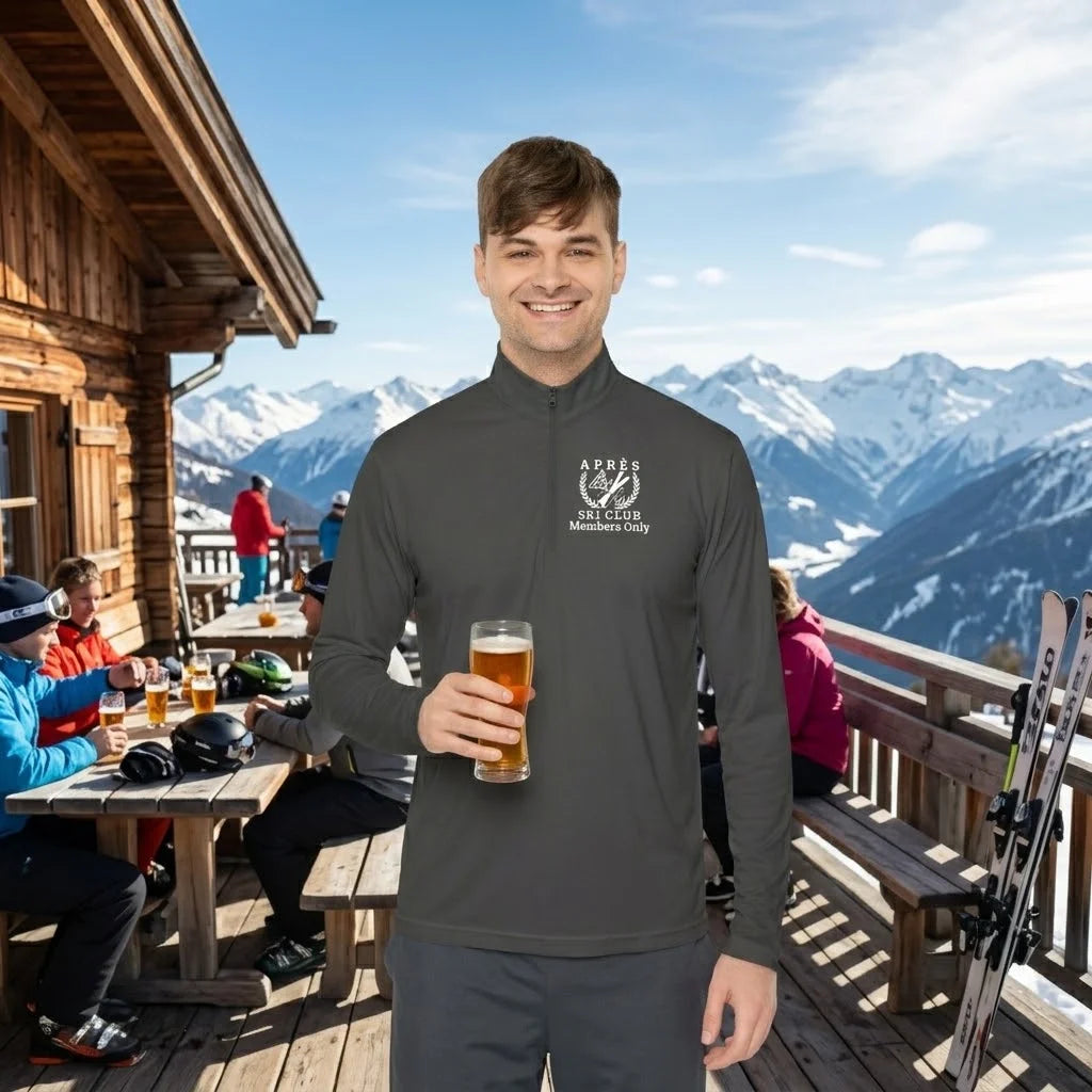Ski Pullover A man wearing a dark gray long-sleeve quarter-zip pullover with a white 'Ski Resorts Chamonix' logo on the left chest, holding a glass of beer on a wooden mountain chalet deck with snowy peaks in the background.