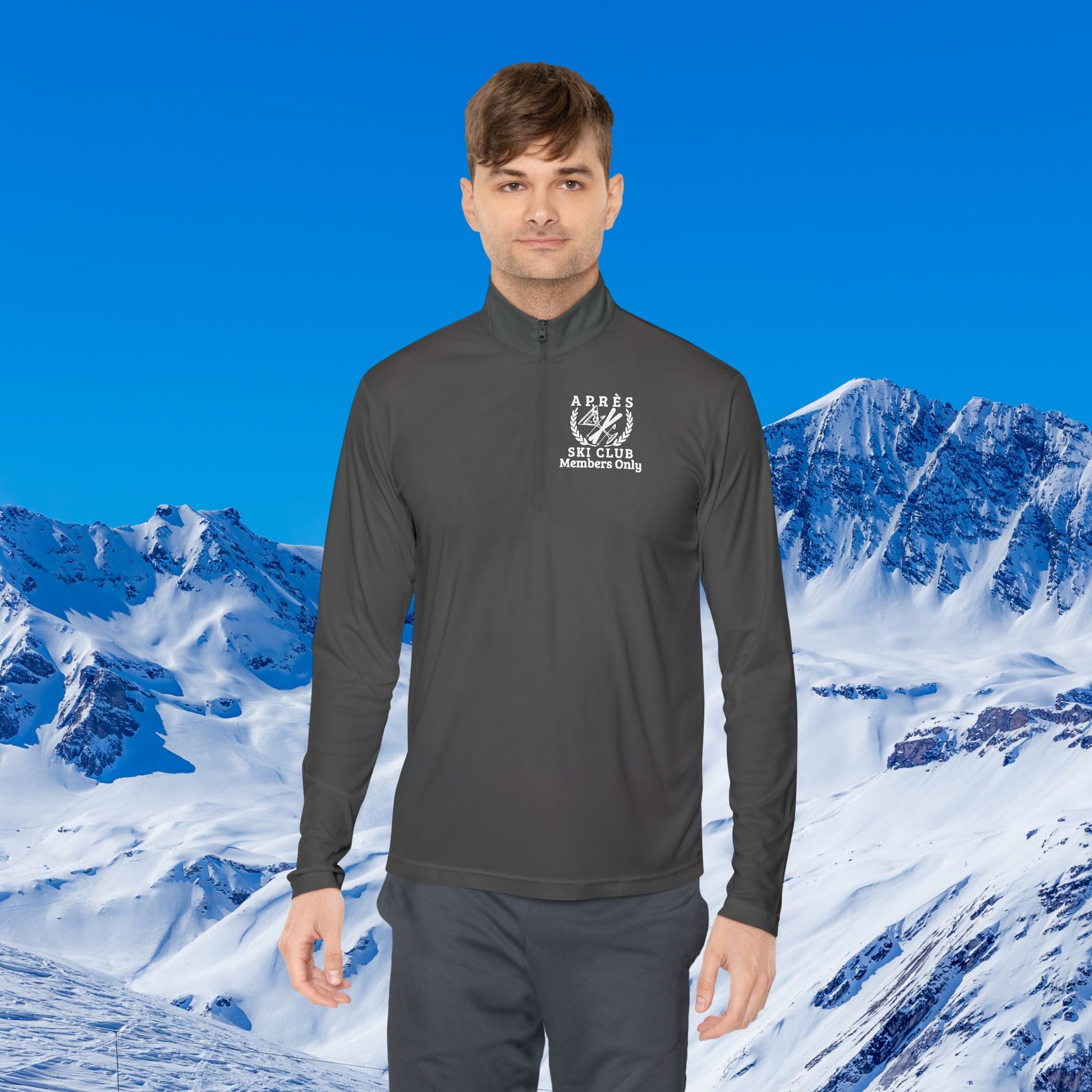 Ski Pullover A man wearing a dark gray long-sleeve quarter-zip athletic pullover with a white 'AGNES SKI CLUB Adventure Club' logo on the left chest, set against a bright blue sky and snowy mountain background.