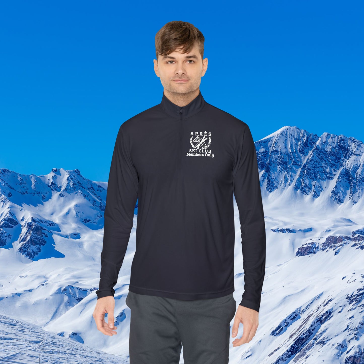 Ski Pullover A man wearing a black long-sleeve quarter-zip athletic pullover with a white printed logo on the left chest, set against a bright blue sky and snowy mountain background.
