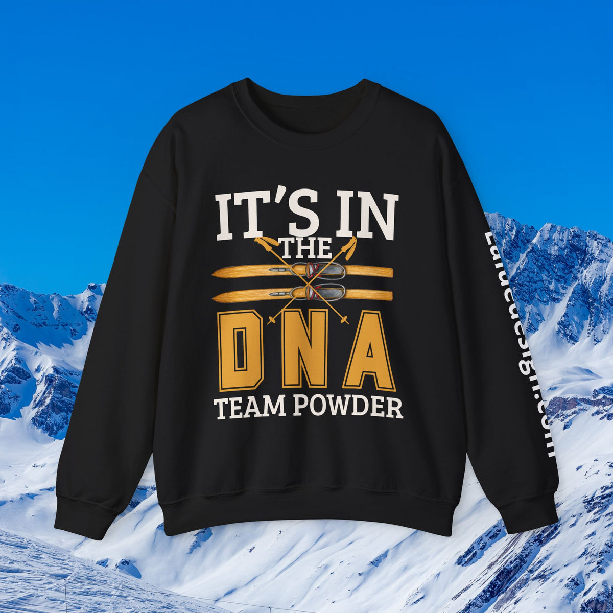 Ski Sweatshirt A black crewneck sweatshirt with a graphic print reading 'IT'S IN THE DNA TEAM POWDER' in white and gold, featuring crossed skis and snowboard graphics. The sweatshirt is displayed against a digital background of snowy mountains and a blue sky.