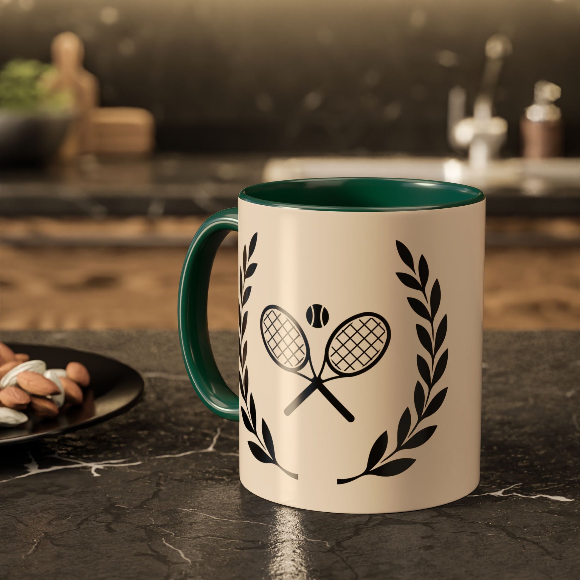 Tennis Coffee Mug A ceramic mug with a cream-colored exterior, dark green interior and handle, and a black tennis-themed graphic featuring crossed rackets, a tennis ball, and laurel wreaths, set on a dark marble countertop in a blurred kitchen environment.