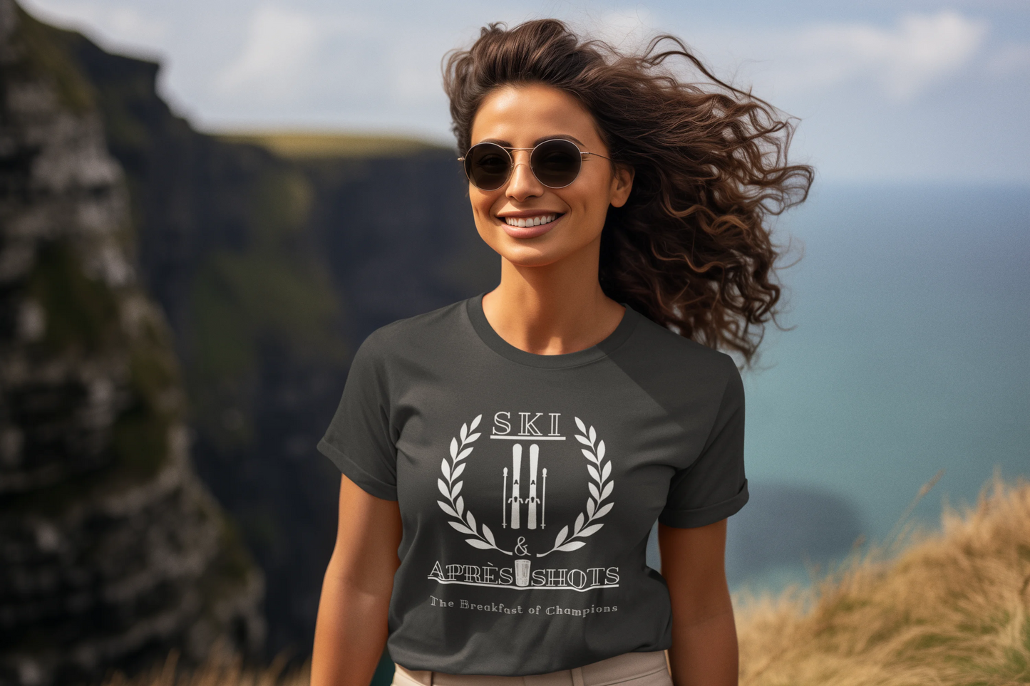 Woman wearing a t-shirt with a logo and text, standing outdoors with mountains in the background
