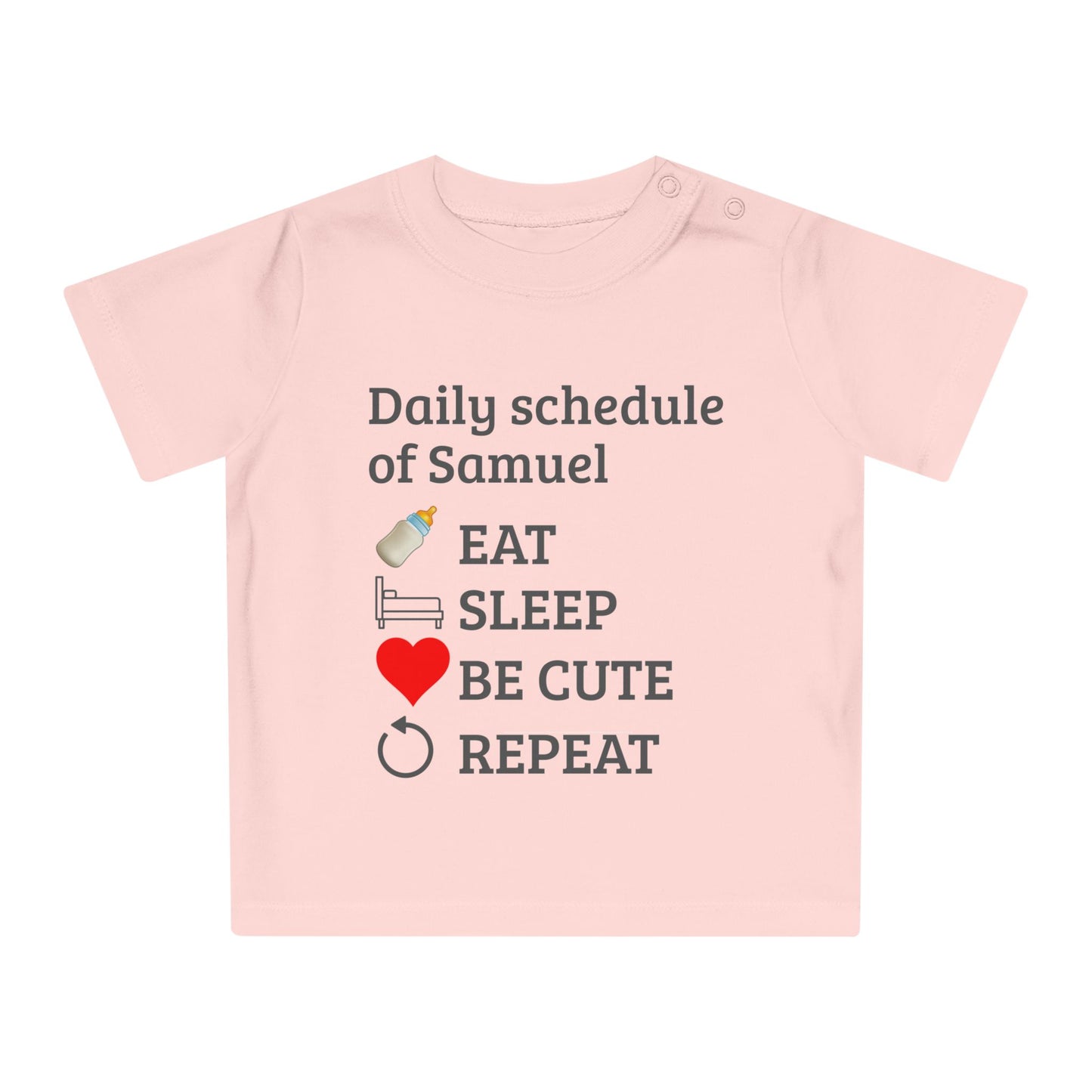 baby gift idea A light pink short-sleeve baby t-shirt with a dark gray text graphic reading 'Daily schedule of Samuel' followed by baby icons and words: 'EAT', 'SLEEP', 'BE CUTE', 'REPEAT'.