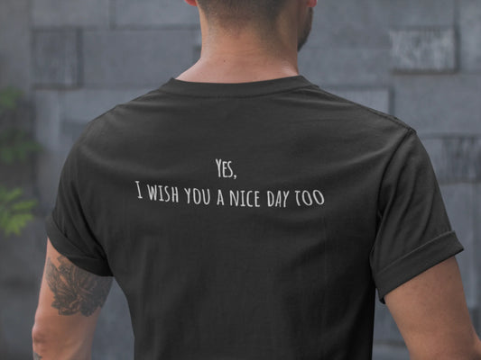 Person wearing a black t-shirt with text on the back, standing against a stone wall.