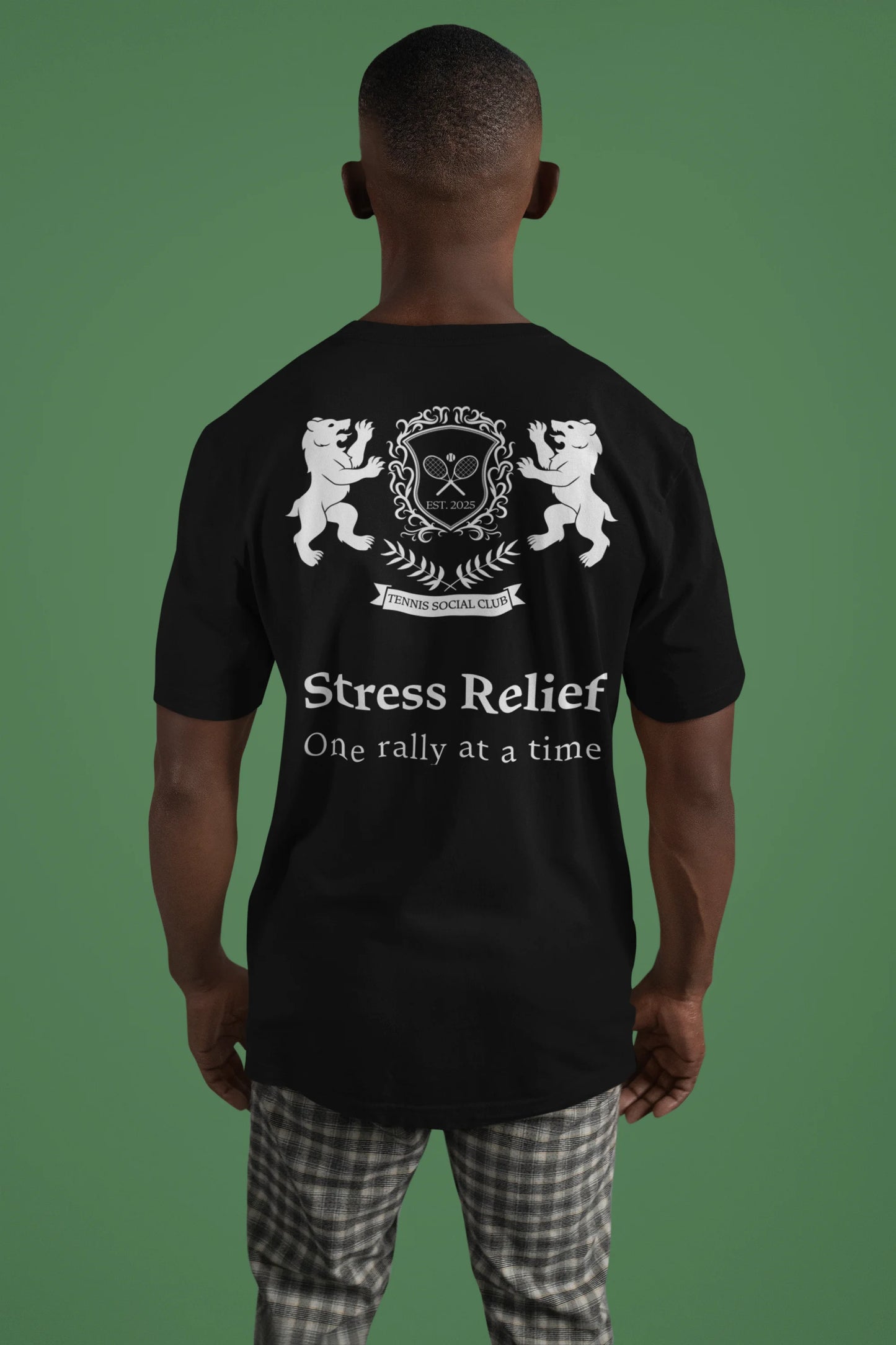 Person wearing a black t-shirt with white text and design on the back, against a green background