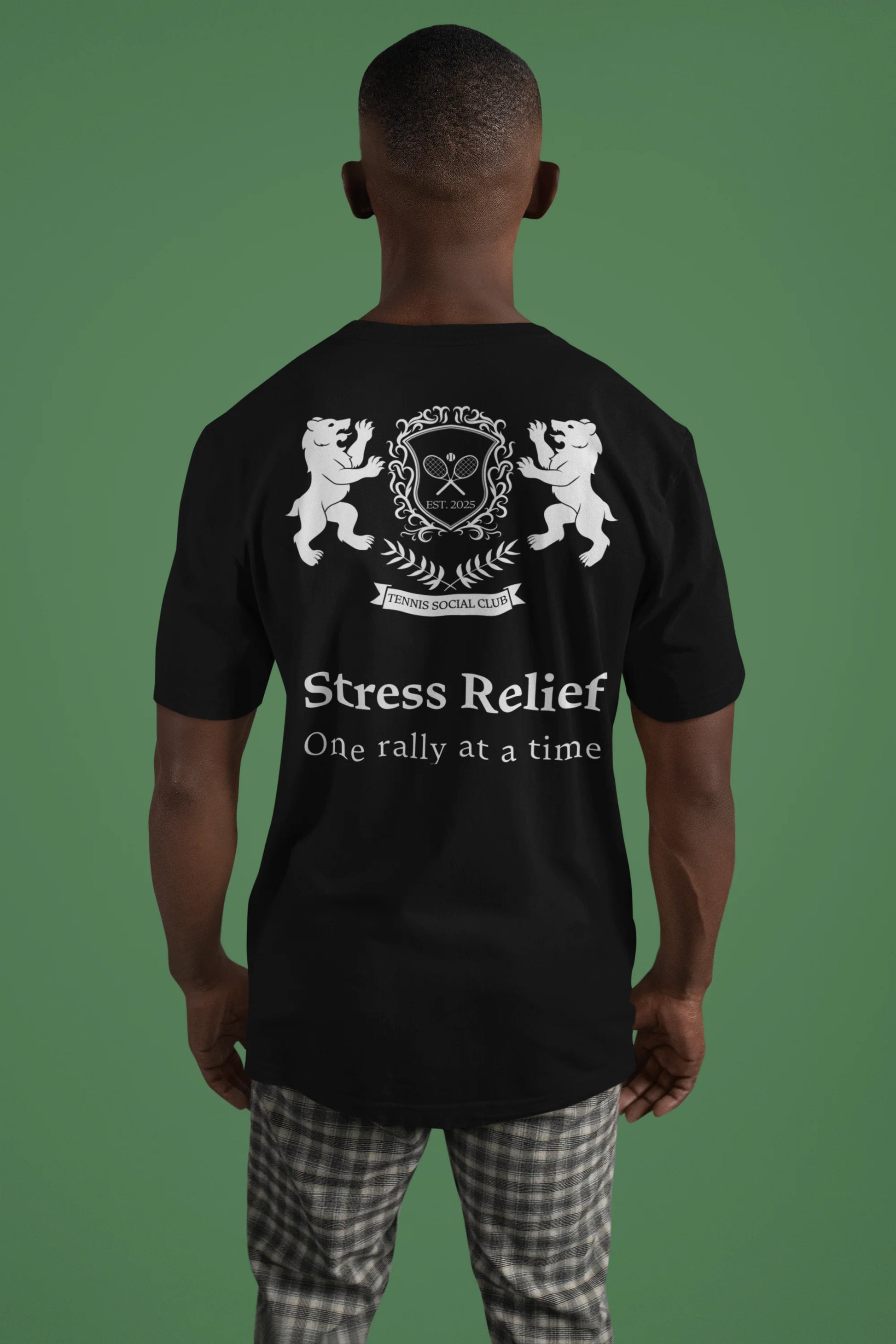 Person wearing a black t-shirt with white text and design on the back, against a green background