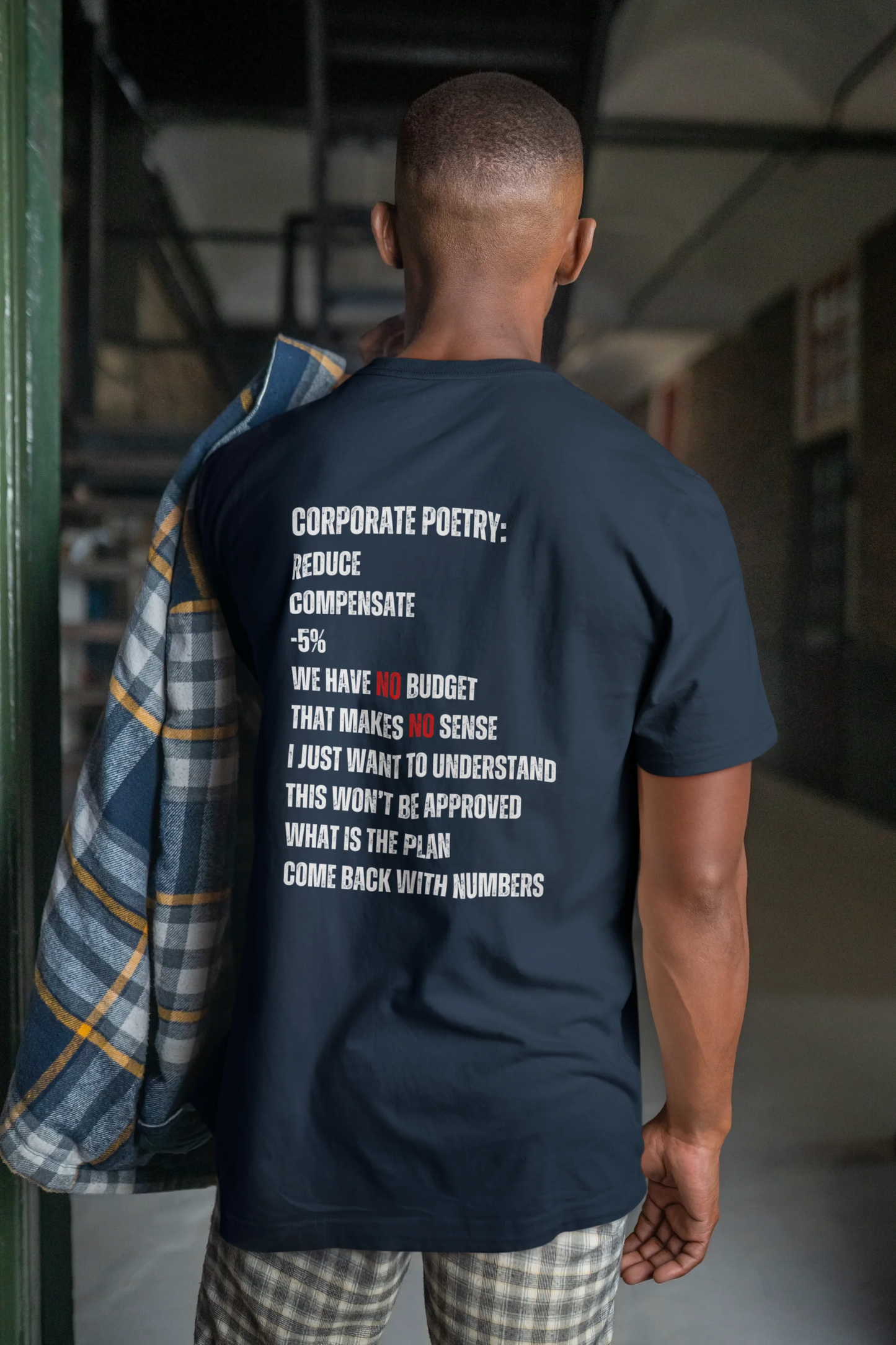 Finance Controller Shirt Person wearing a navy blue t-shirt with text on the back in an indoor setting.