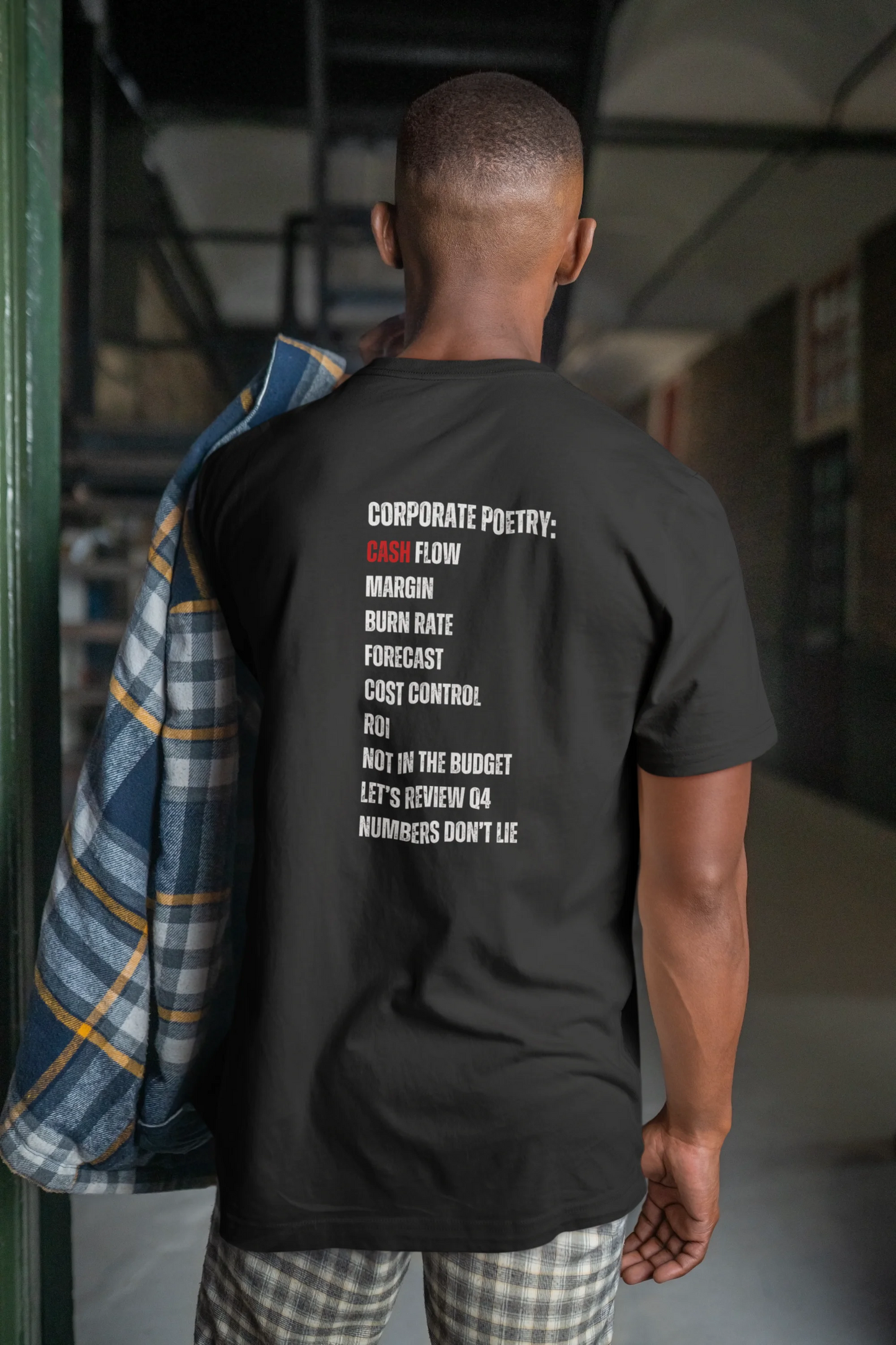 Finance Manager Shirt Person wearing a black t-shirt with text on the back in an indoor setting