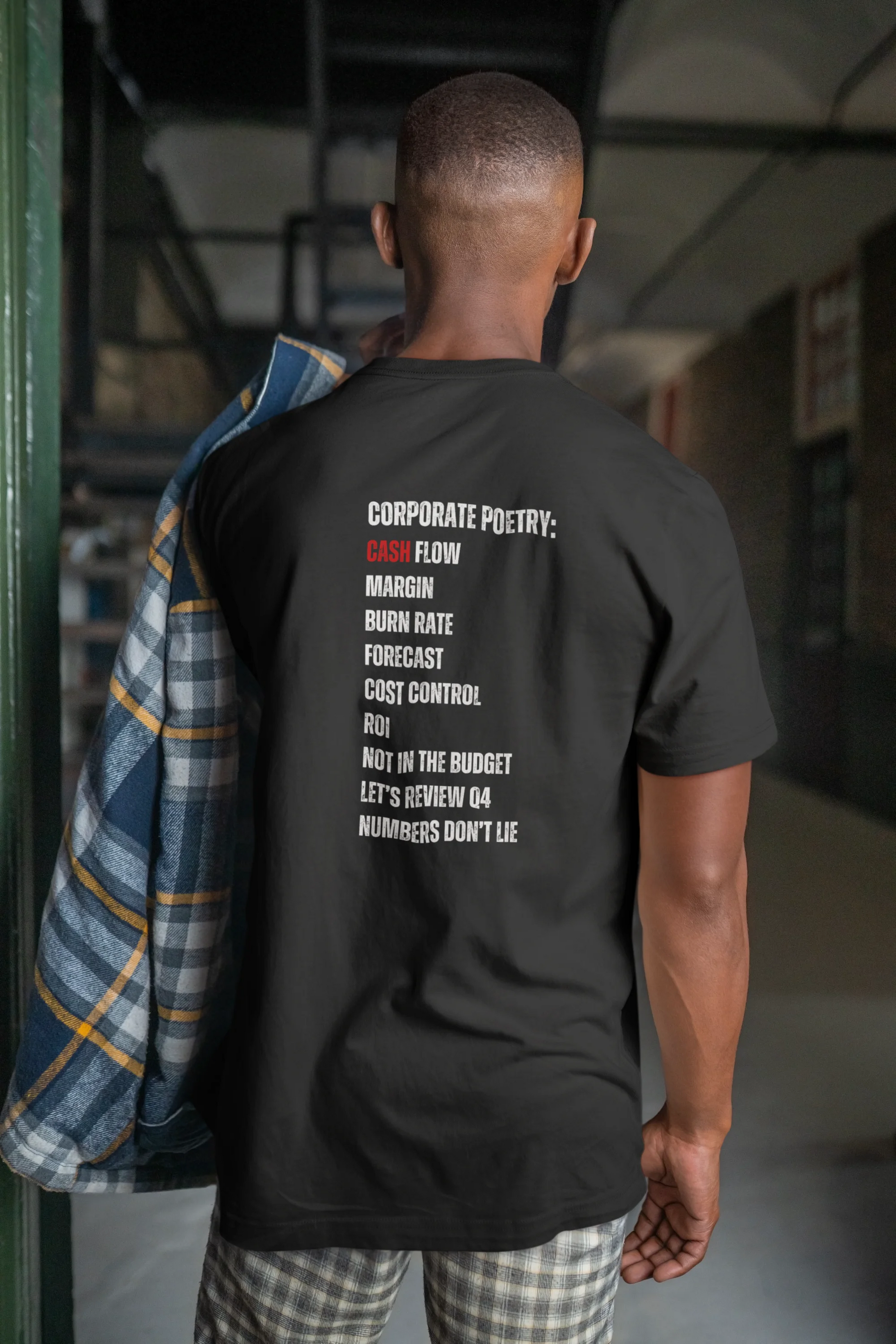 Finance Manager Shirt Person wearing a black t-shirt with text on the back in an indoor setting