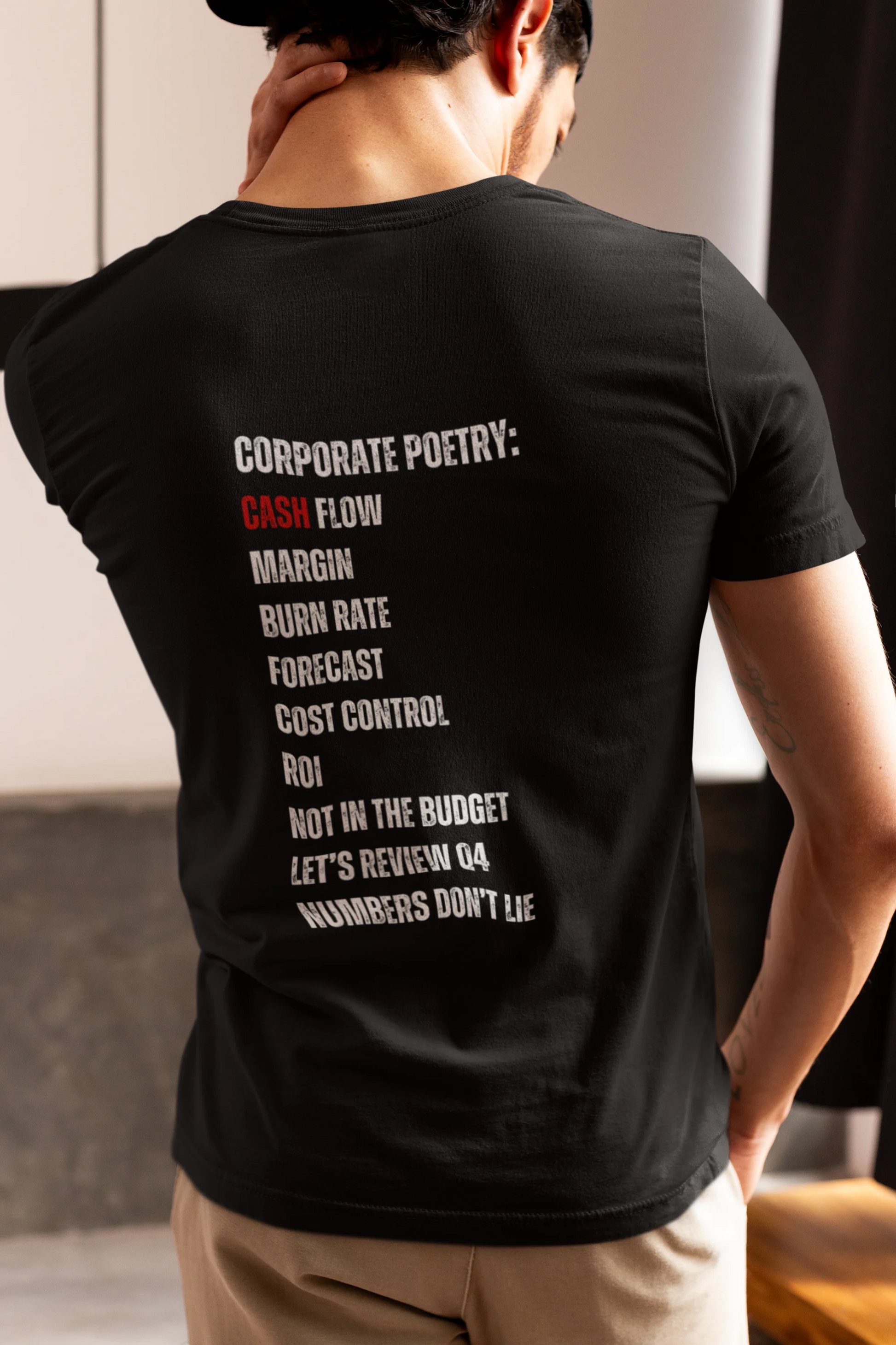 Finance Manager Shirt Person wearing a black t-shirt with text on the back, standing indoors.