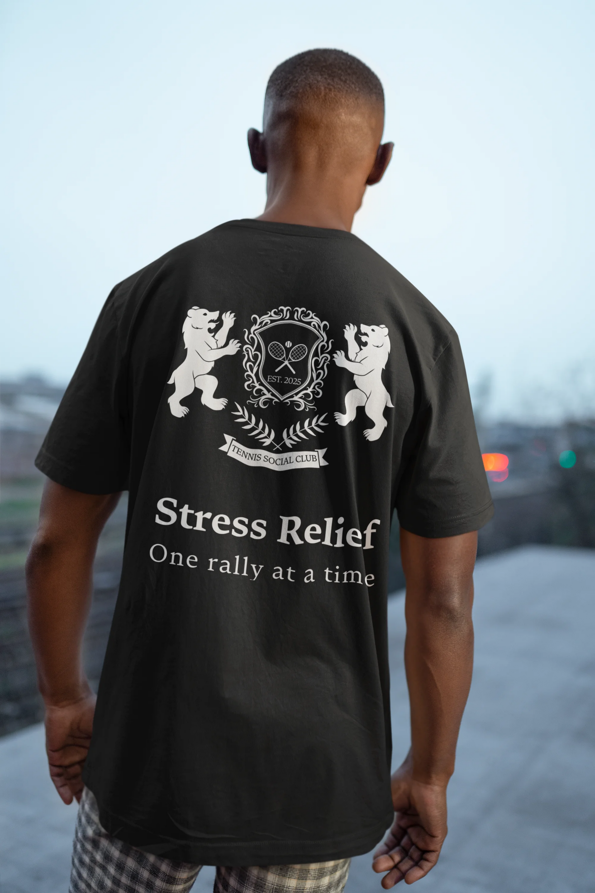 Person wearing a black t-shirt with a graphic and text on the back, standing outdoors.