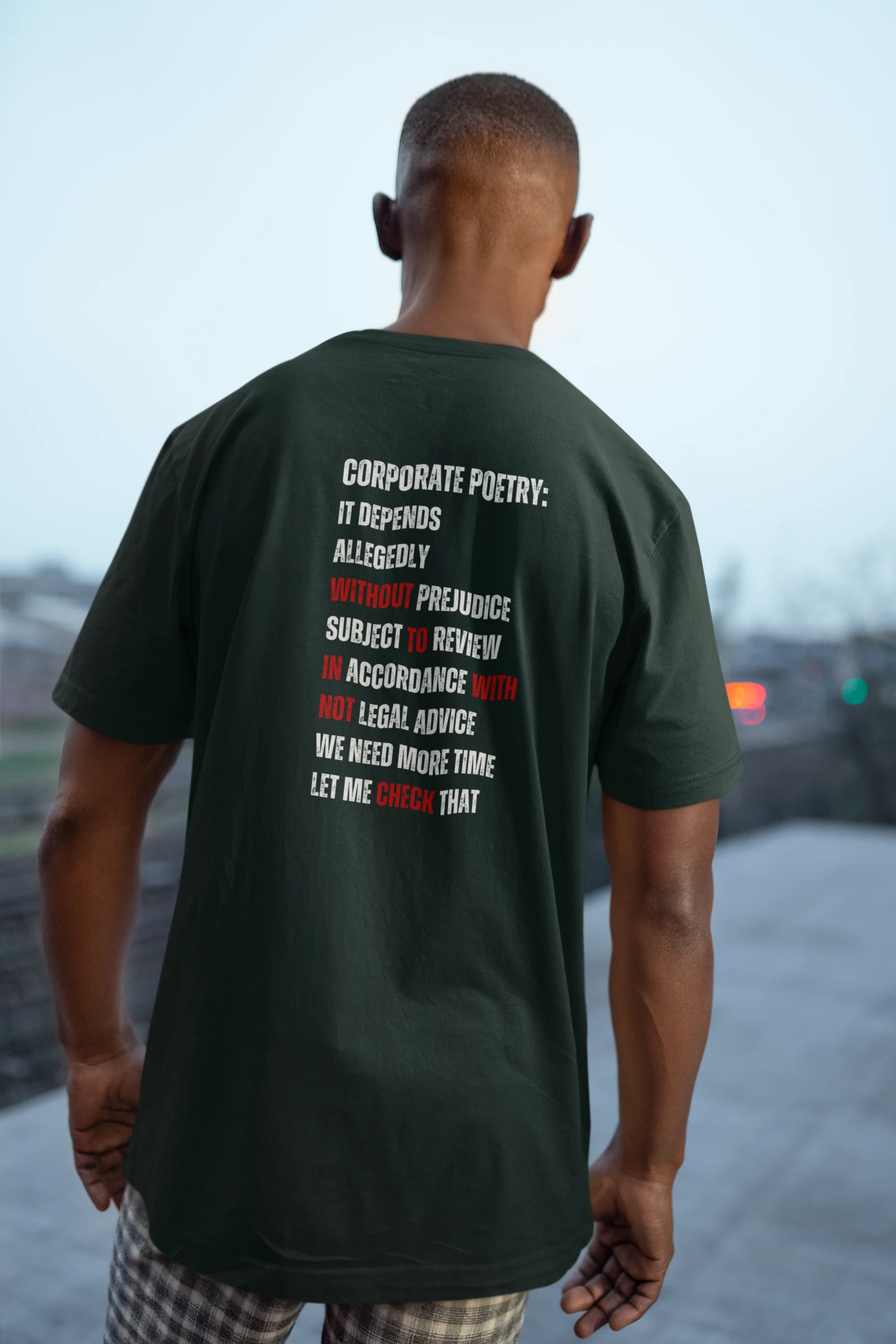 Funny Lawyer Shirt Man wearing a dark green t-shirt with text on the back, standing outdoors.