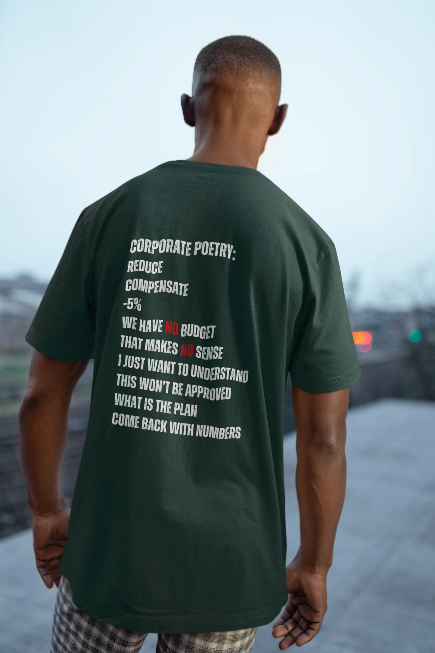 Man wearing a green t-shirt with text on the back, standing outdoors.