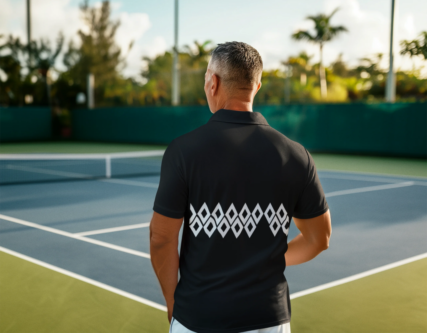 Man wearing a black shirt with a logo on the back, standing on a tennis court.