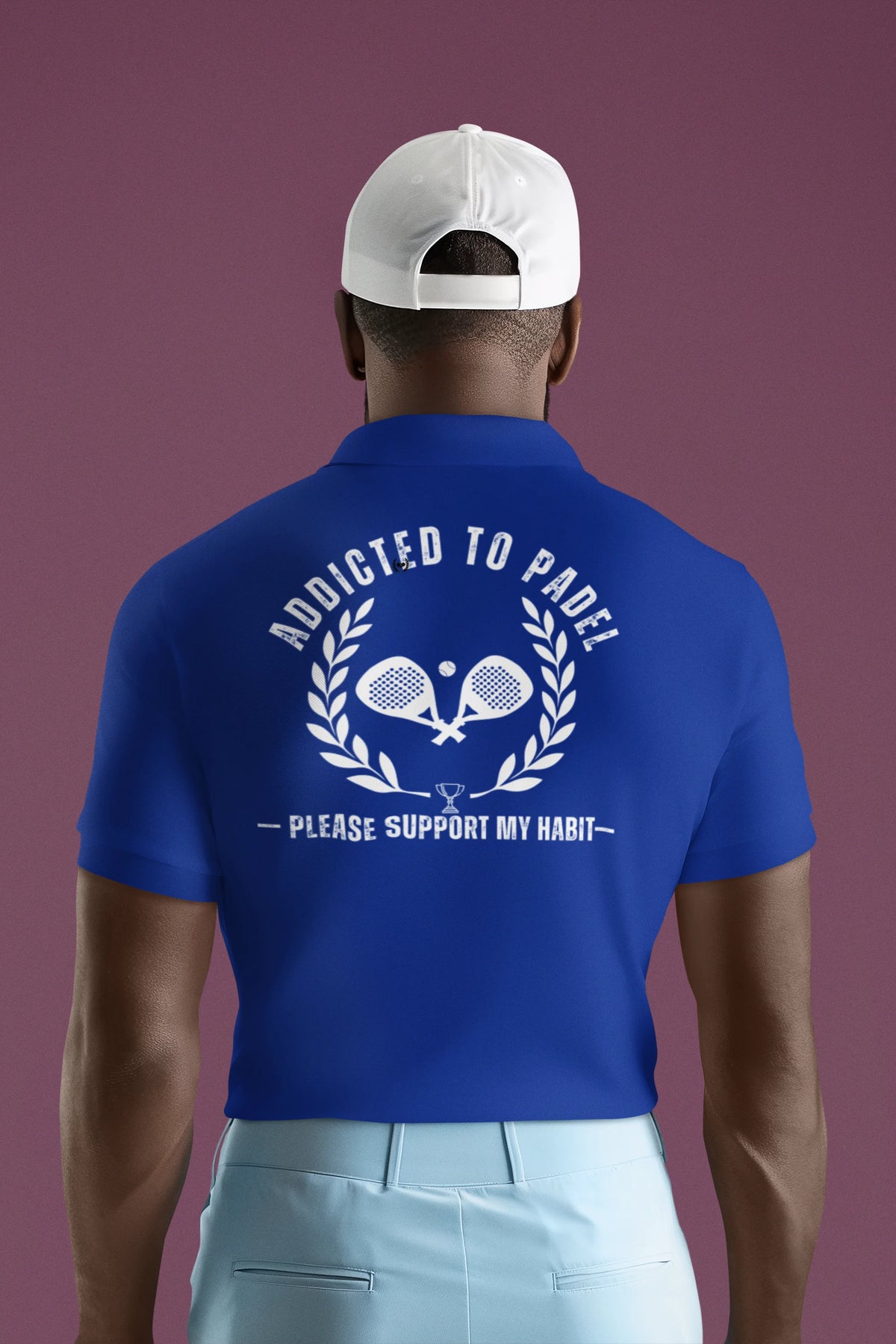 addicted to padel Man wearing a blue polo shirt with text and graphics on the back against a purple background