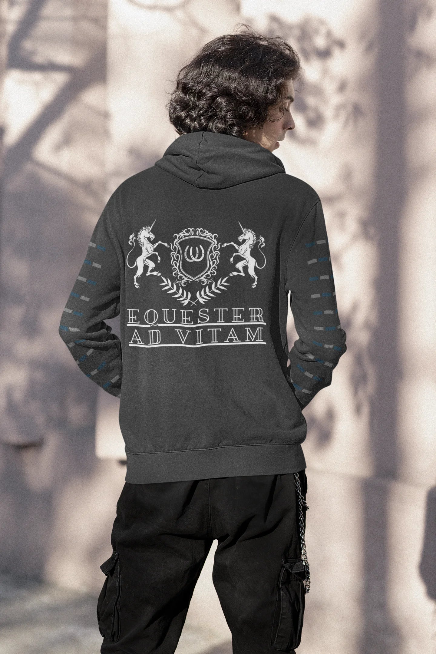 Person wearing a dark hoodie with white text and designs outdoors