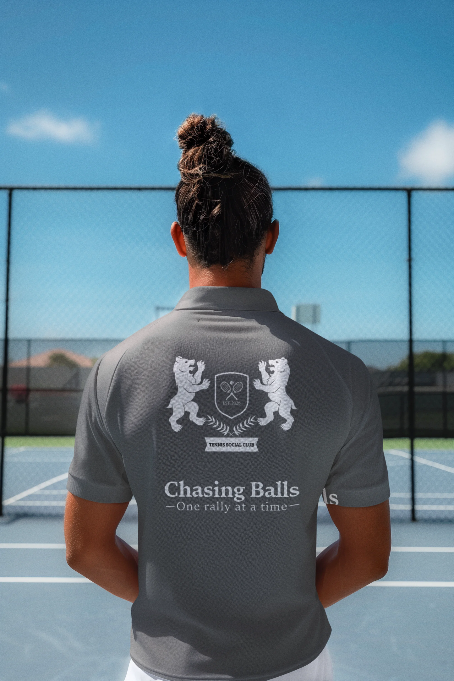 Person wearing a gray polo shirt with 'Chasing Balls' logo on a tennis court