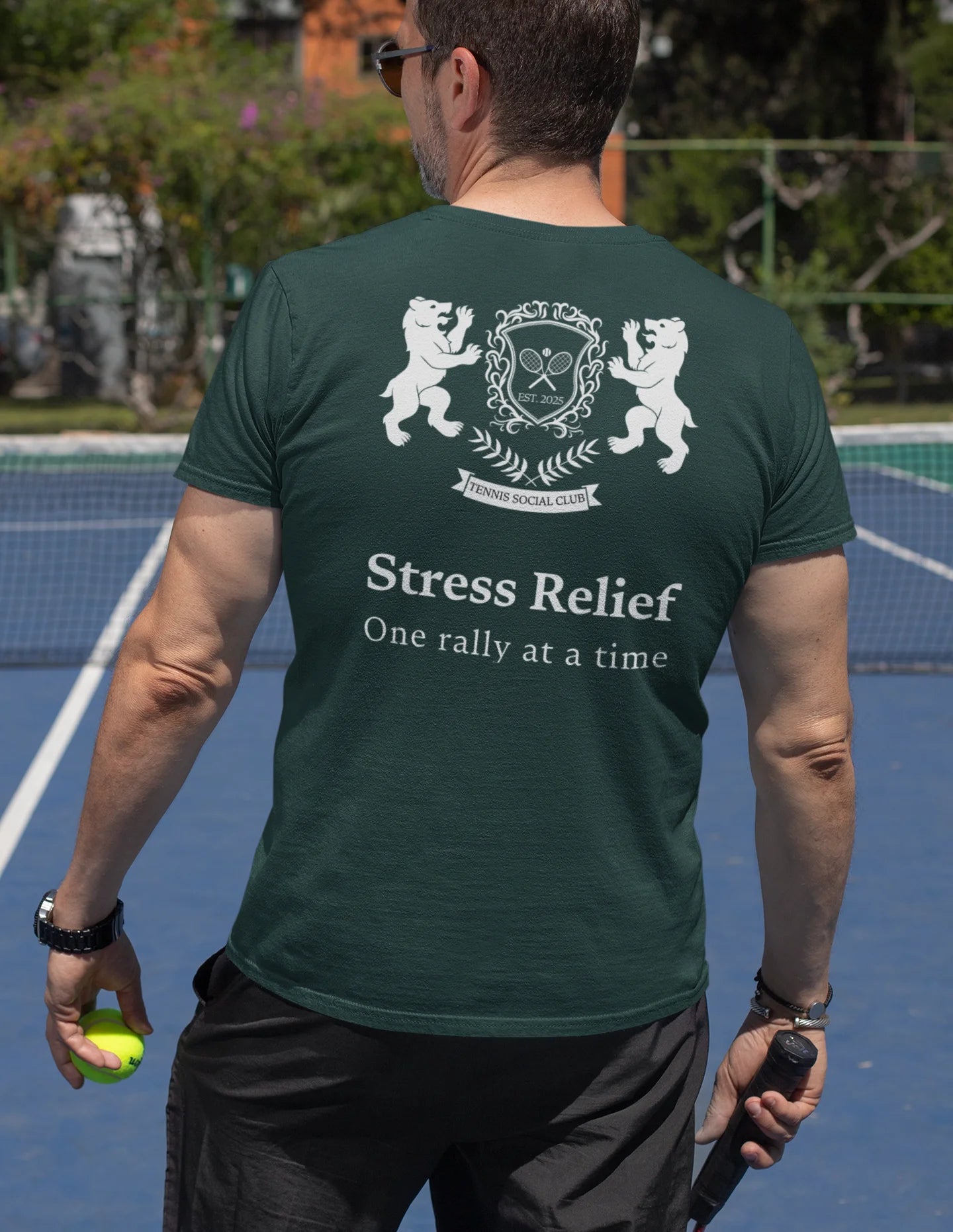 Man wearing a green t-shirt with a tennis-themed design on a tennis court