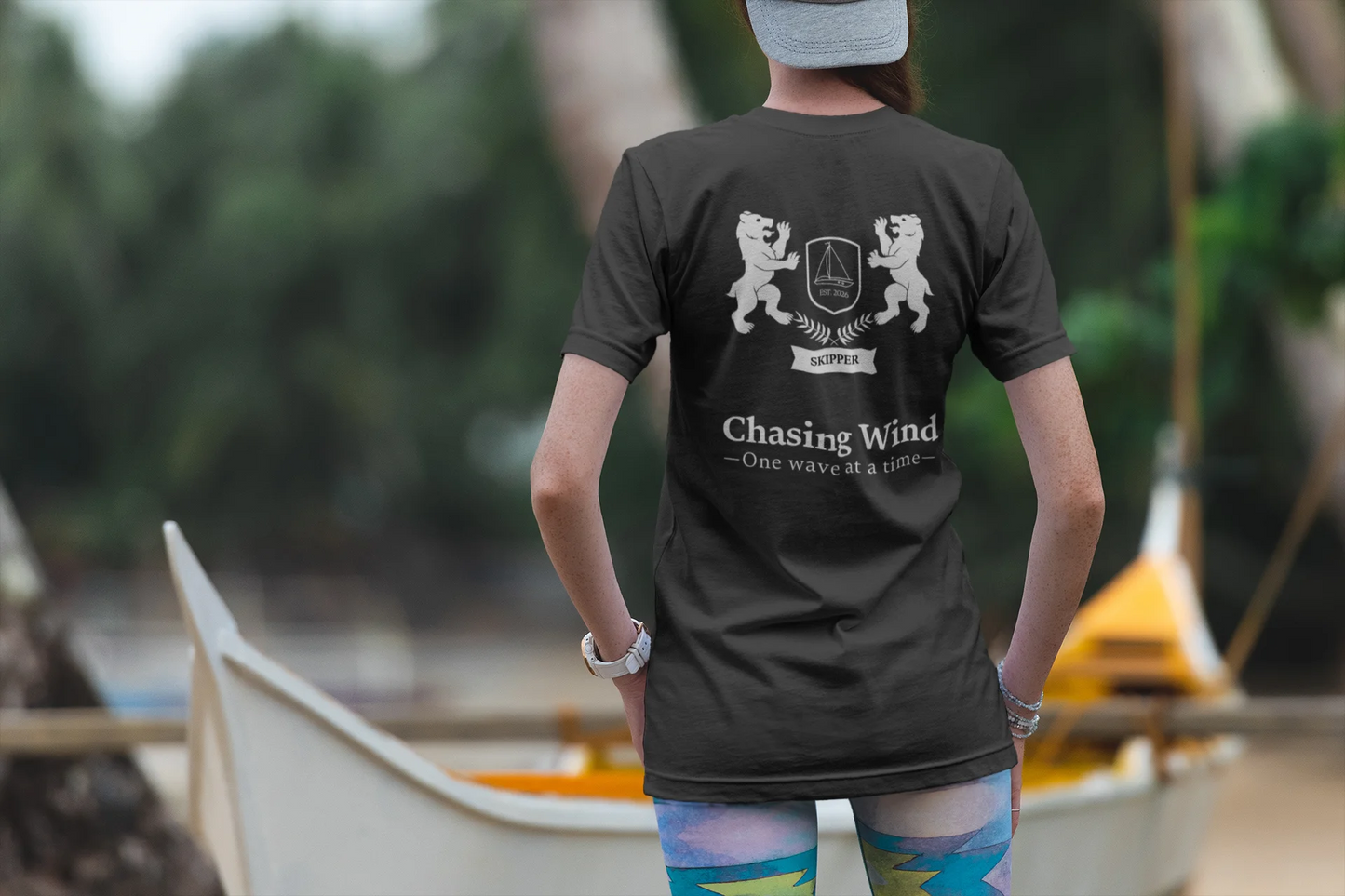 Sailing T-Shirt Person wearing a black t-shirt with text and graphics, standing outdoors near boats.