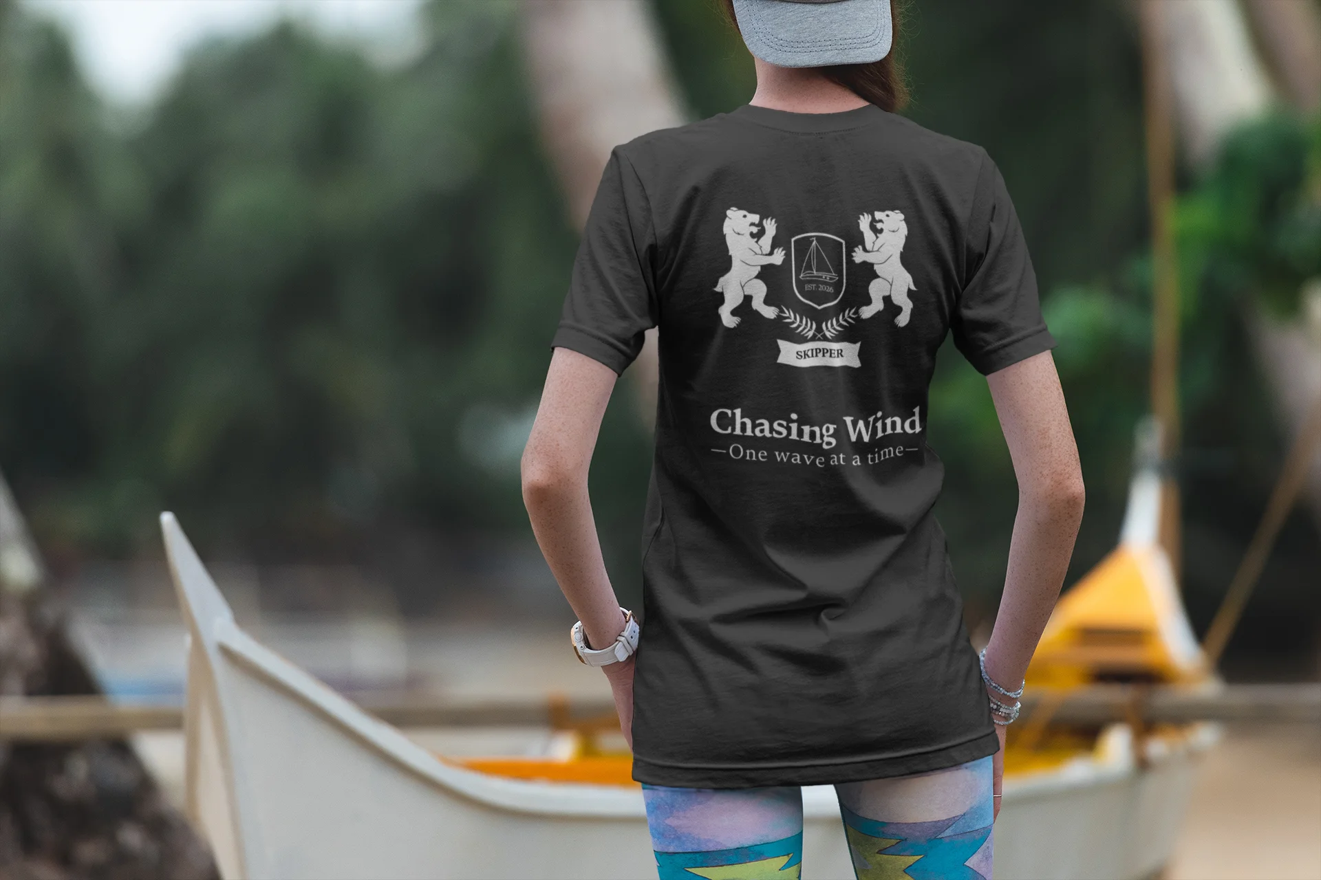 Sailing T-Shirt Person wearing a black t-shirt with text and graphics, standing outdoors near boats.