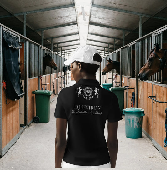 barn to street Person wearing a black equestrian shirt in a stable with horses and stalls.