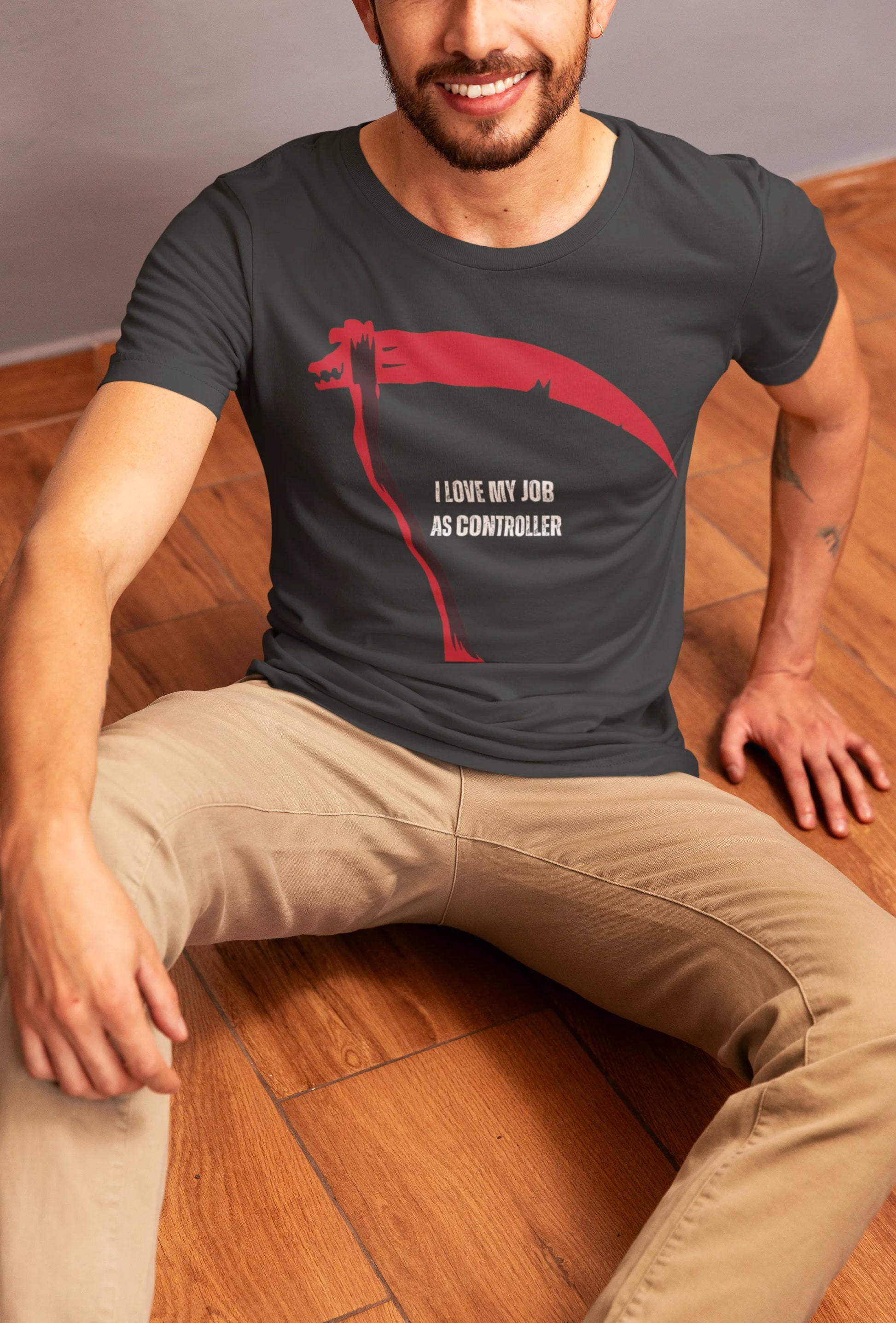 Man wearing a t-shirt with a graphic design and text, sitting on a wooden floor.