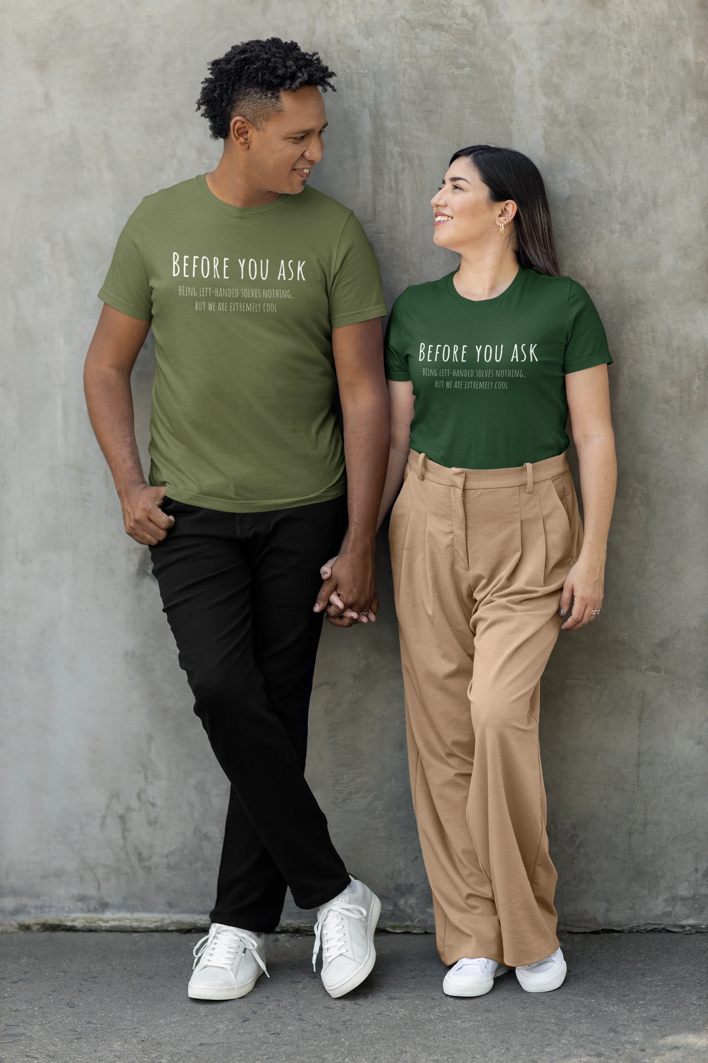 Two people wearing green t-shirts with text against a gray wall.