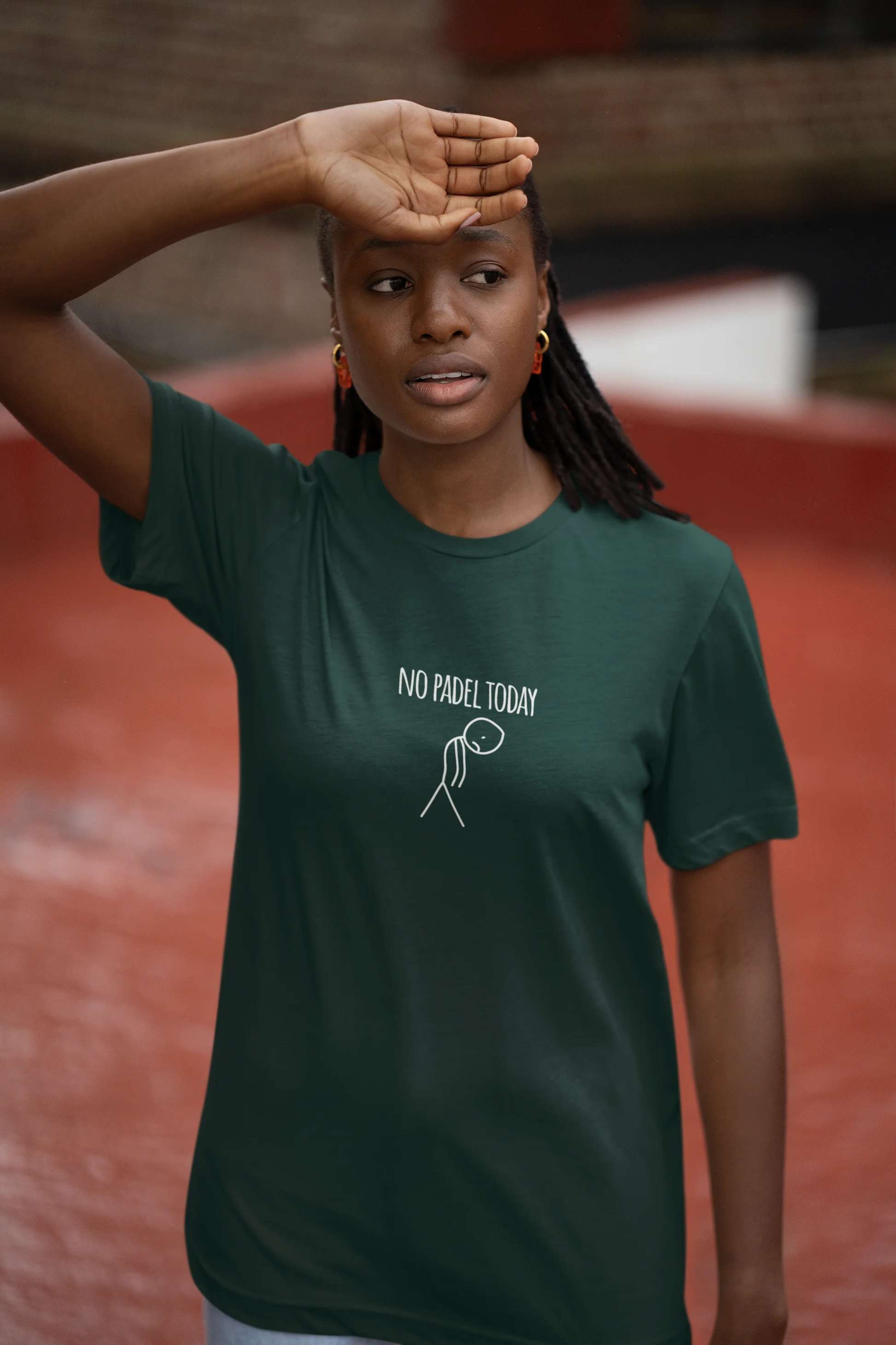 Person wearing a green t-shirt with text and graphic, standing on a red surface.