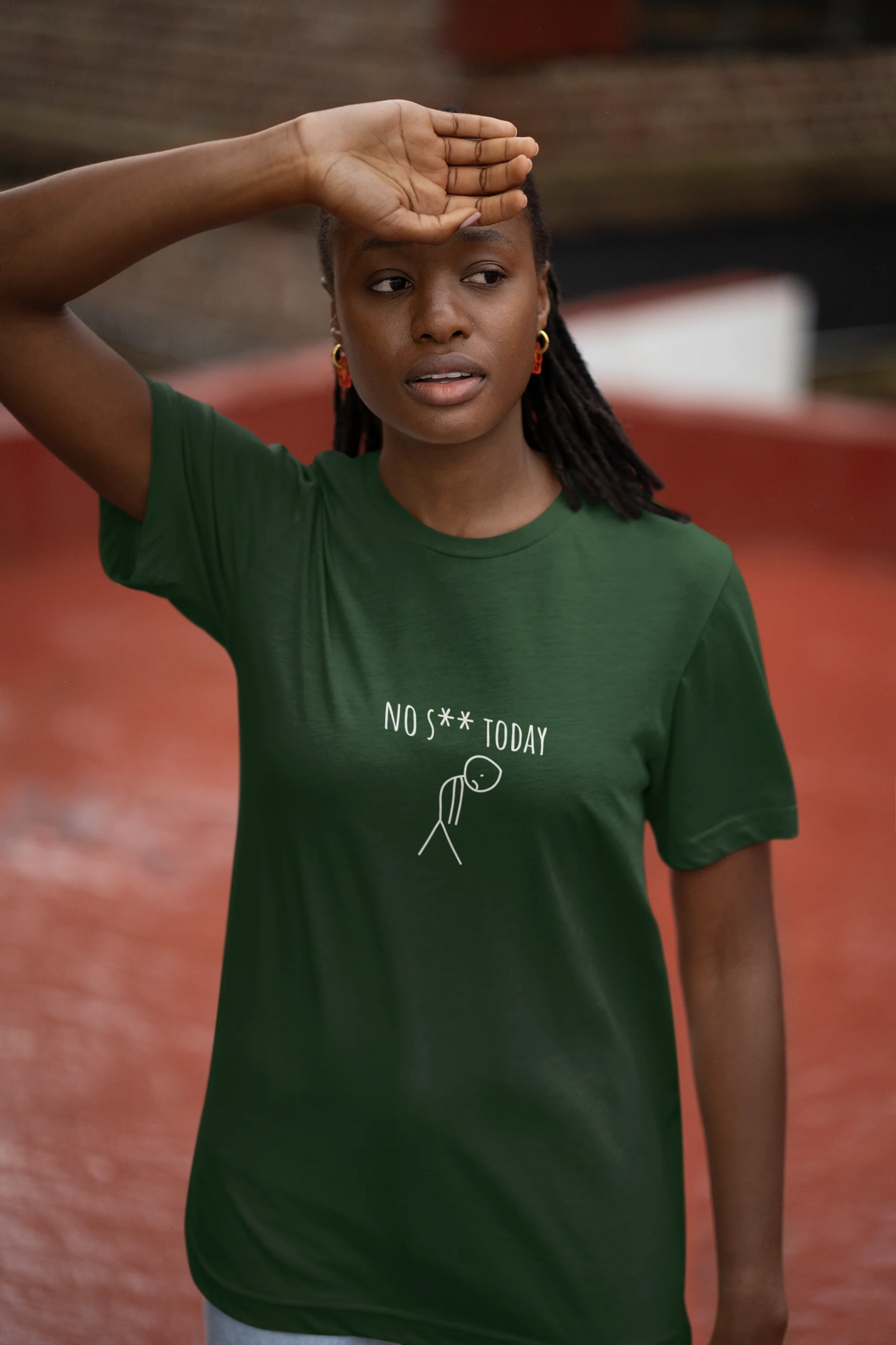 Person wearing a green t-shirt with text and graphic, standing outdoors.