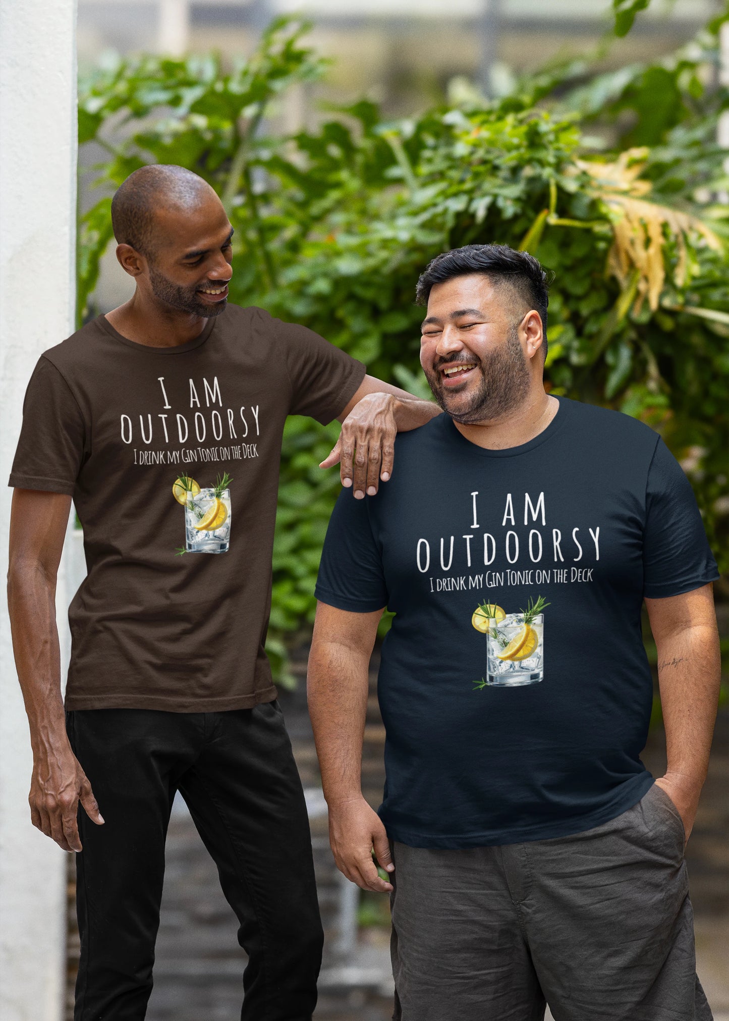 Two men wearing 'I AM OUTDOORSY' t-shirts standing outdoors with plants in the background.