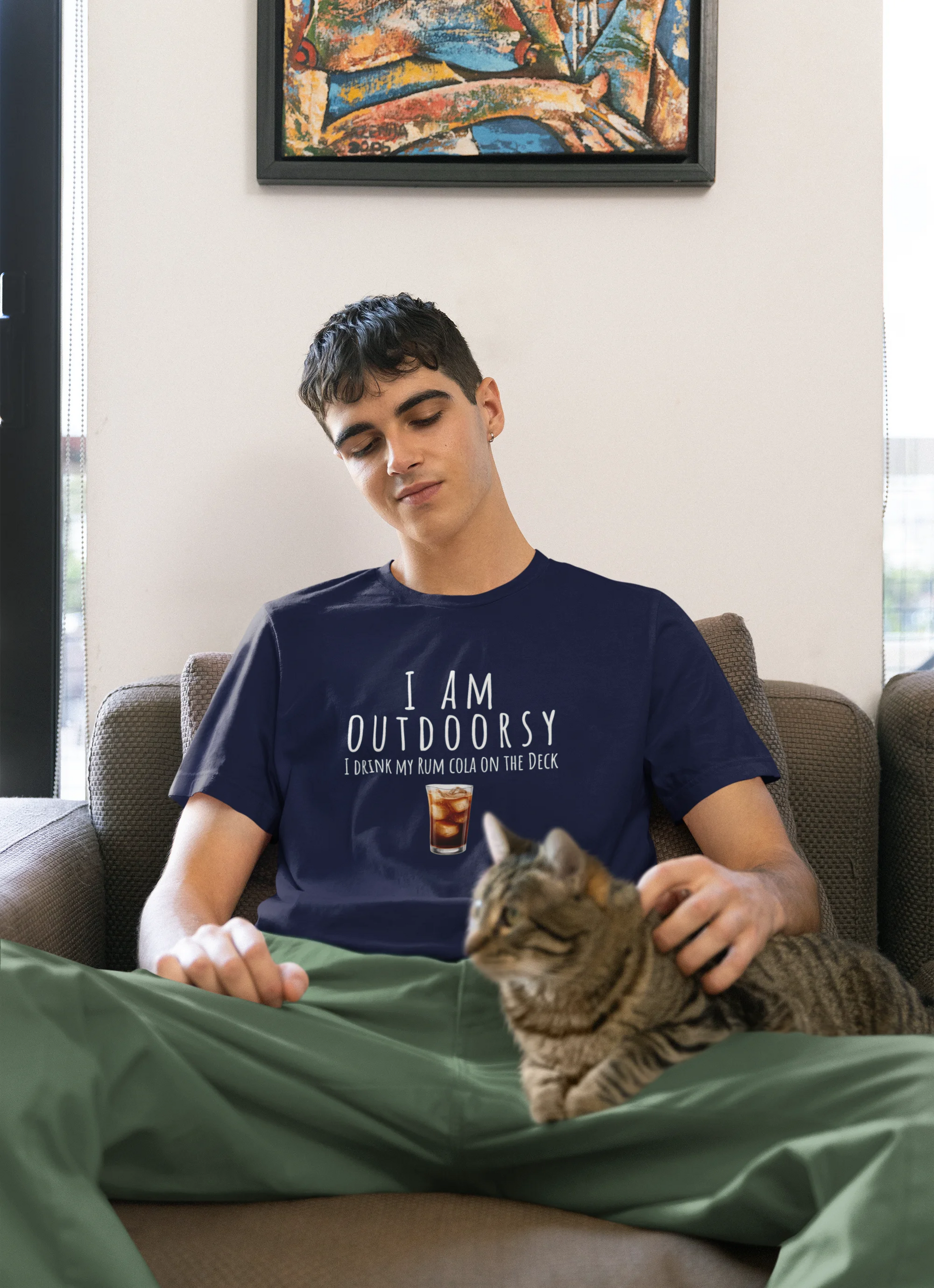Person wearing a navy blue t-shirt with text sitting on a couch with a cat.