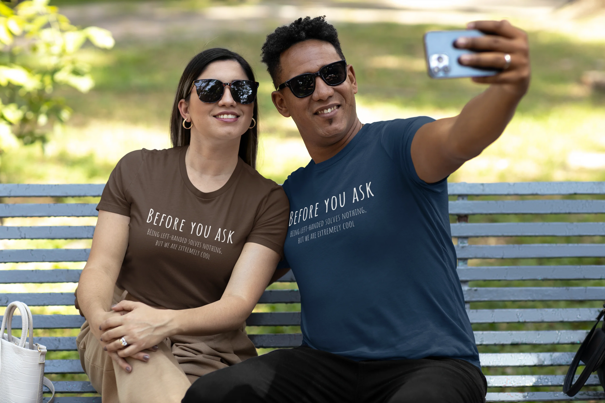 Two people sitting on a bench taking a selfie, wearing matching t-shirts with text.