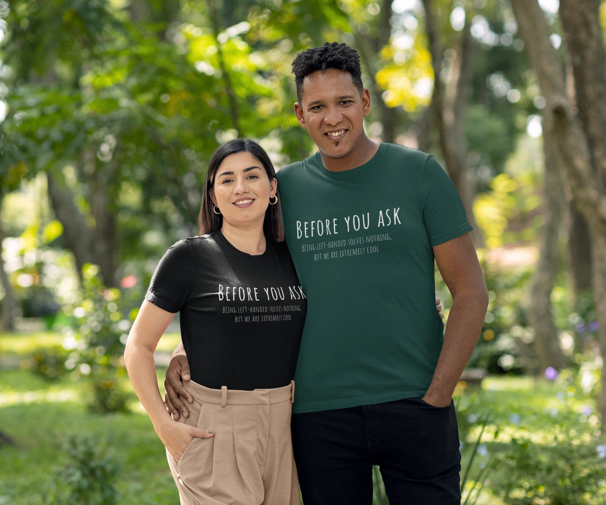 Two people standing outdoors in a park, wearing matching t-shirts with text.
