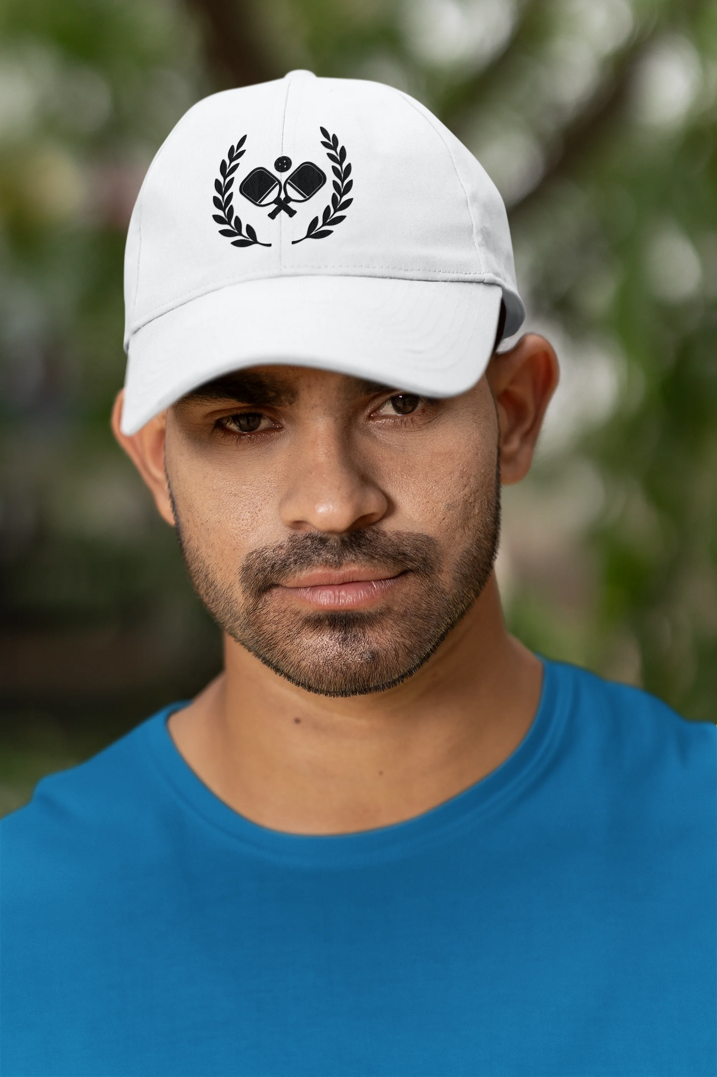 Pickleball  hats Man wearing a white cap with a logo and a blue shirt outdoors