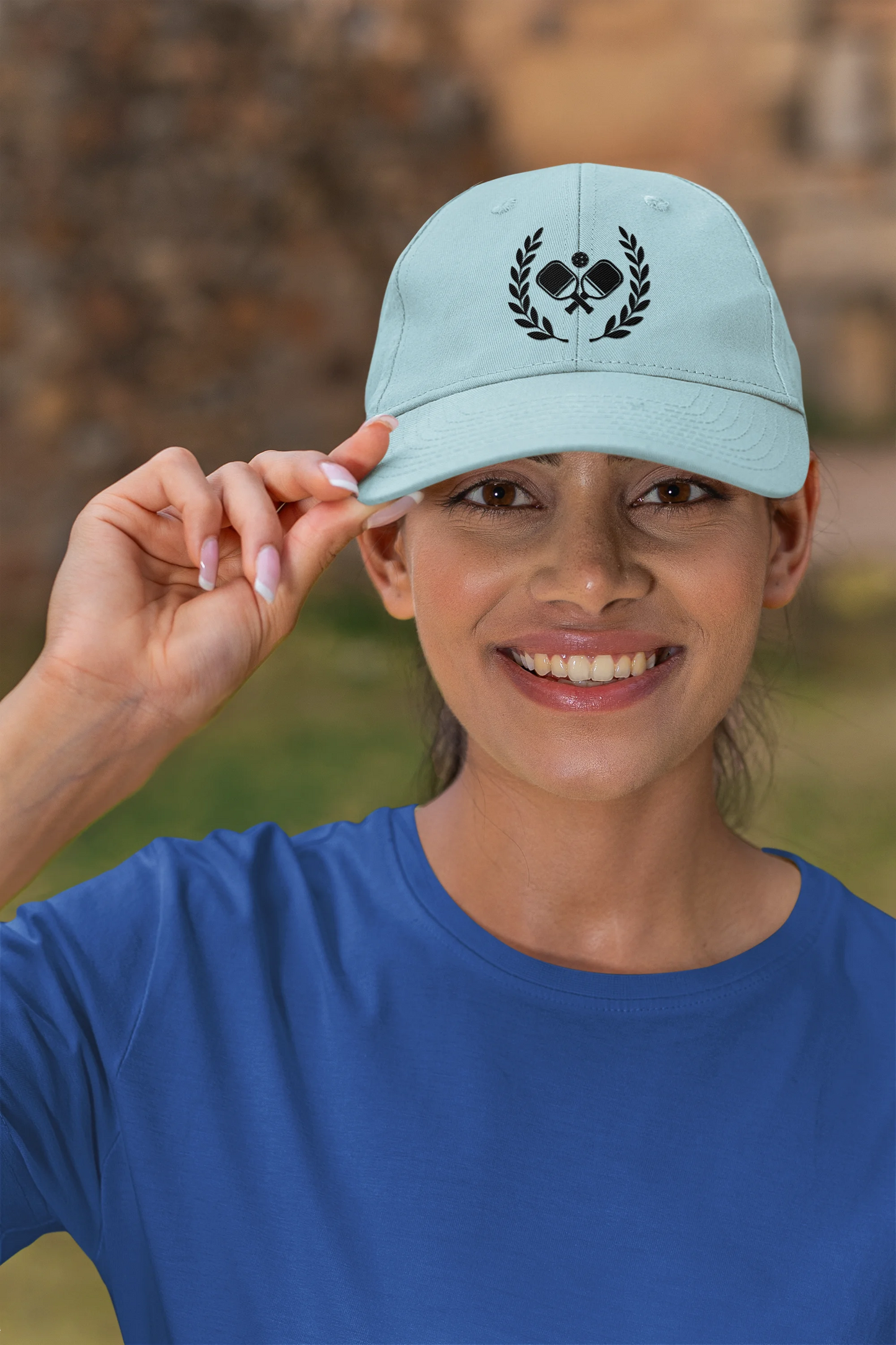 Pickleball  hats Woman wearing a light blue cap with a logo, outdoors.