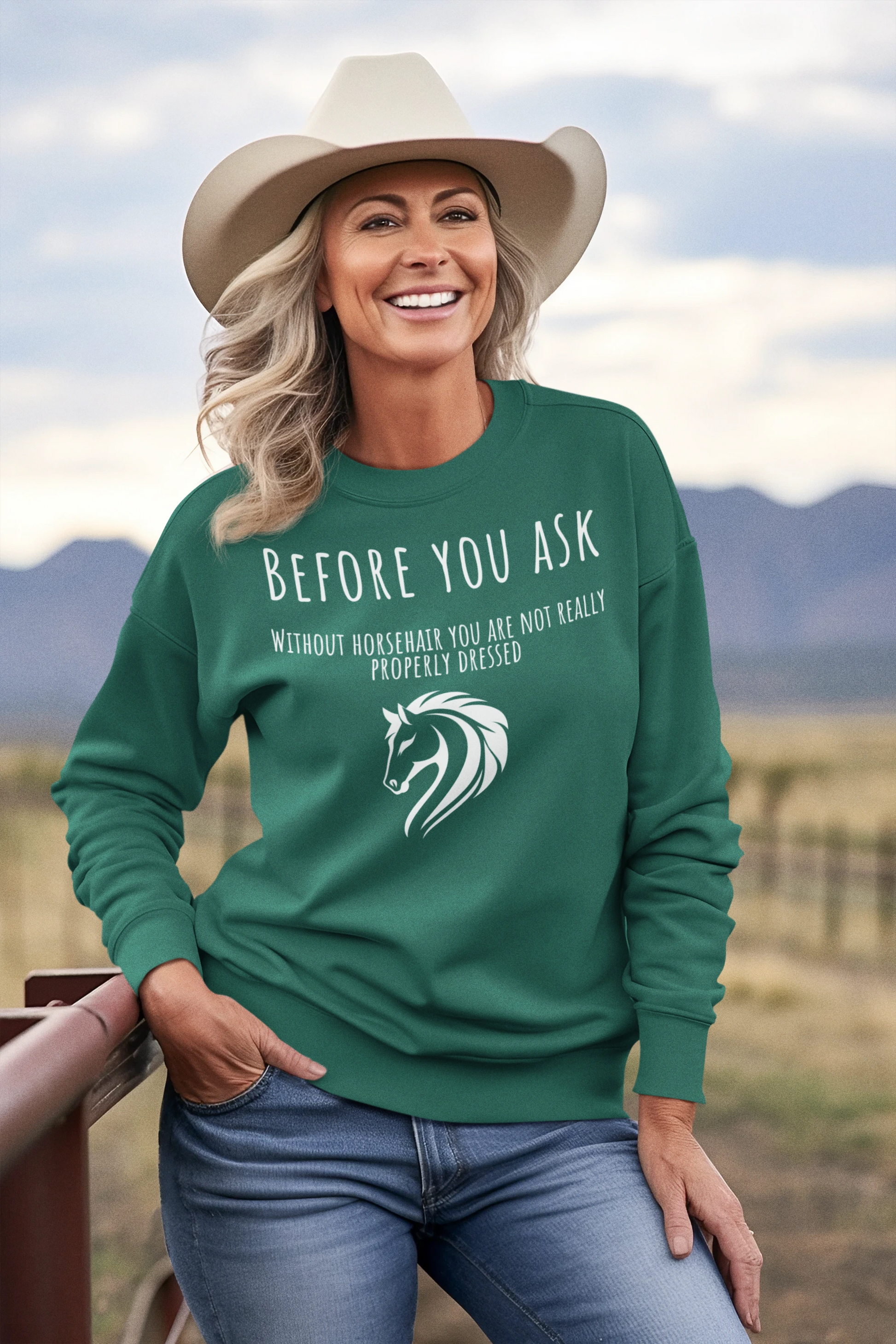 Woman wearing a green sweatshirt with horse-related text and graphics, standing in a scenic outdoor setting.