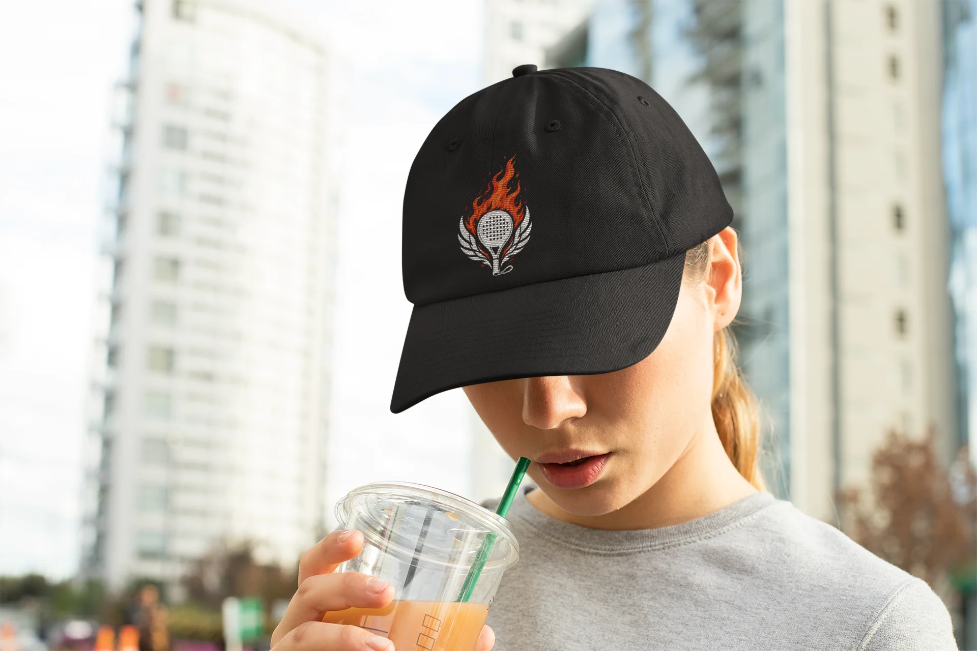 performance padel hat Person wearing a black cap with a white star, drinking from a Starbucks cup outdoors.