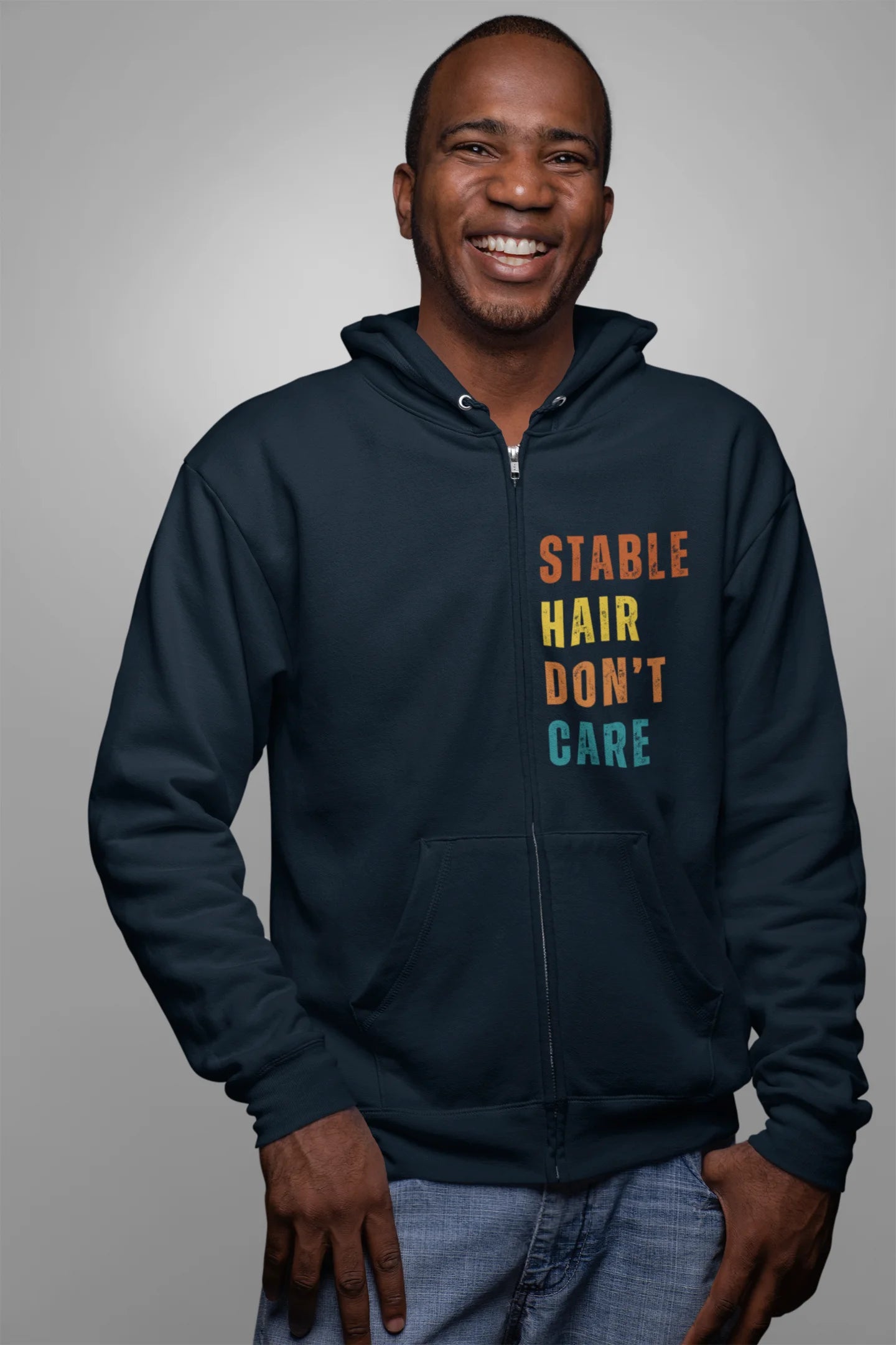 Equestrian Hoodie with Stable Hair Don't Care text and horse barn back print. Man wearing a navy hoodie with 'Stable Hair Don't Care' text on a gray background