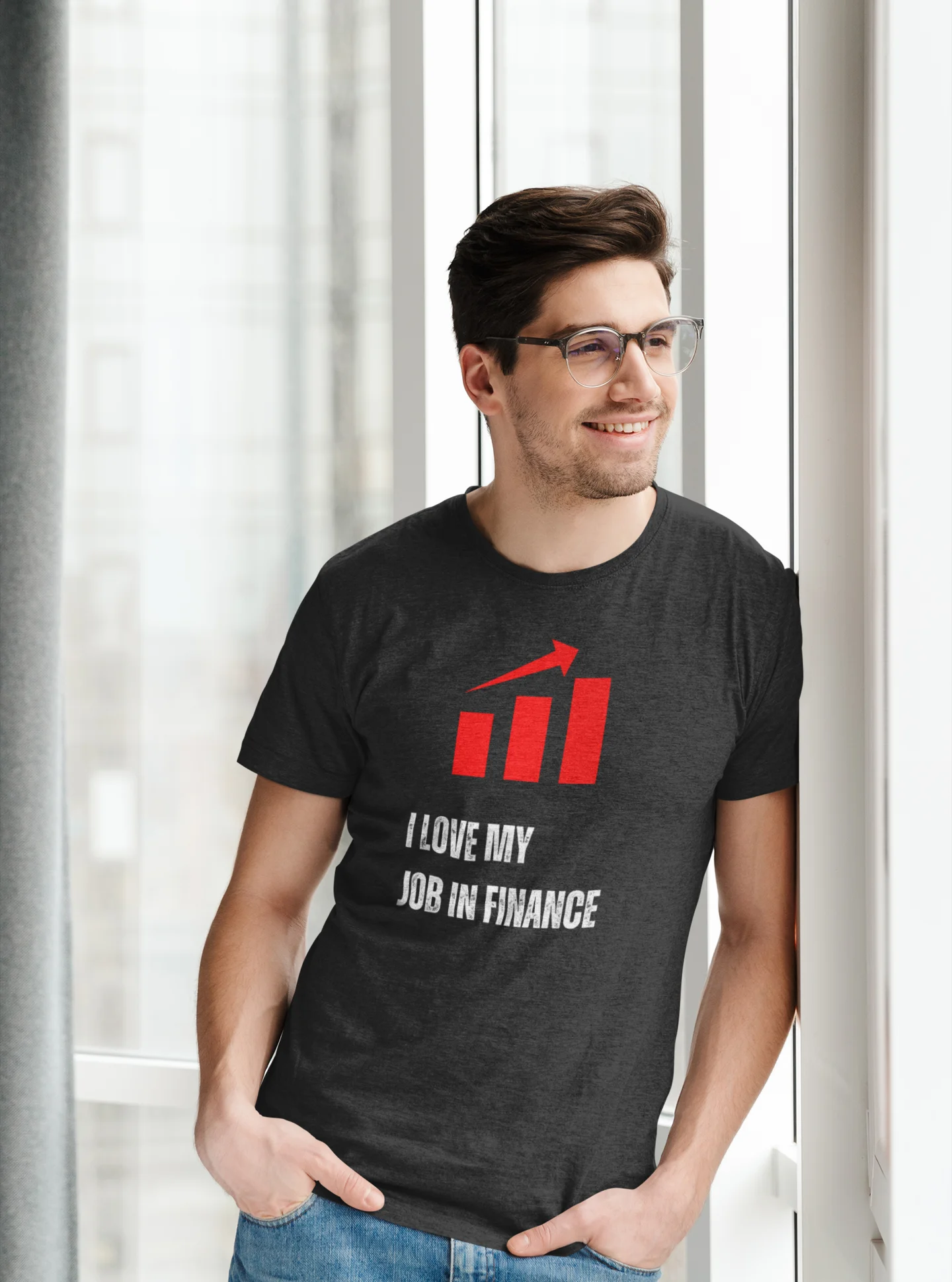 Finance Manager Shirt Man wearing a black t-shirt with a red and white graphic and text, standing indoors.