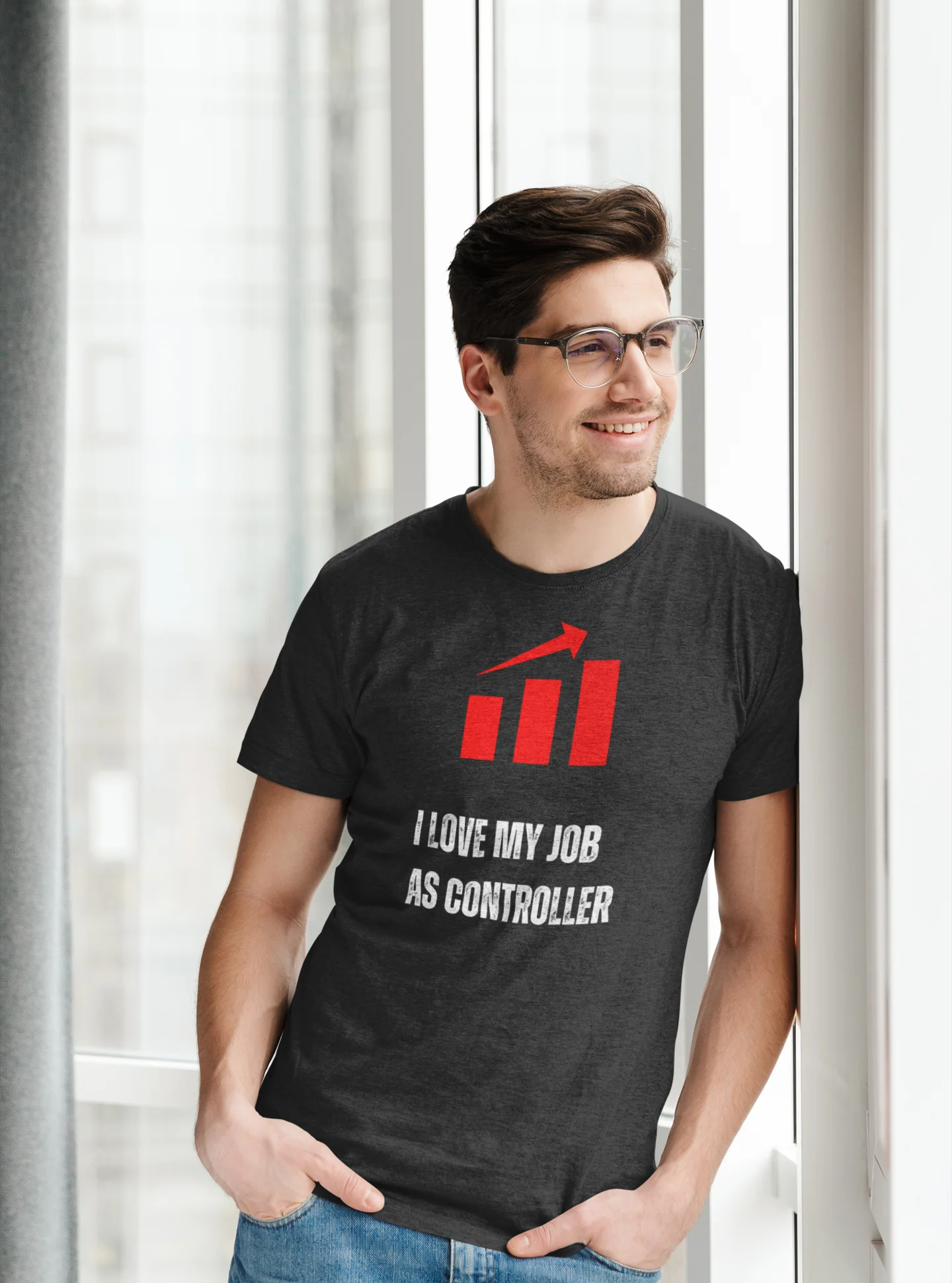 Finance Controller Shirt Man wearing a black t-shirt with a red graphic and text, standing in front of a window.