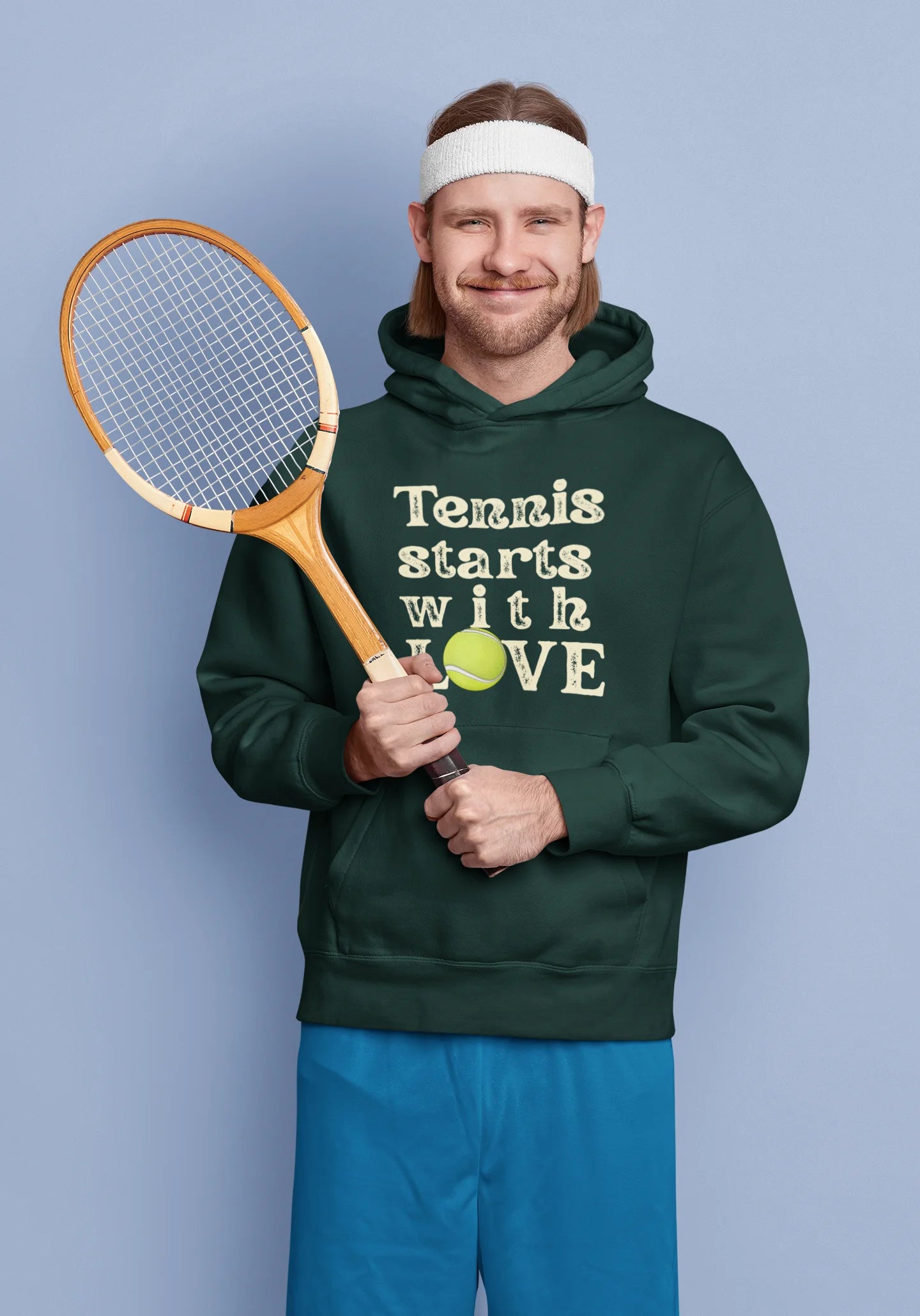 Man holding a tennis racket and a ball, wearing a hoodie with 'Tennis starts with LOVE' text.