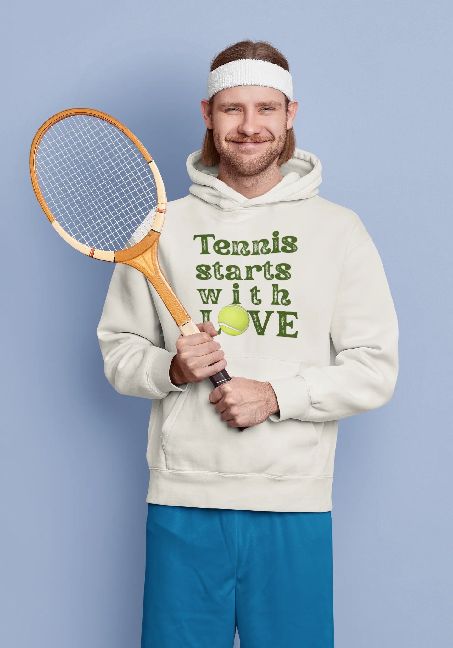 Man holding a tennis racket and wearing a hoodie with 'Tennis starts with LOVE' text on a blue background