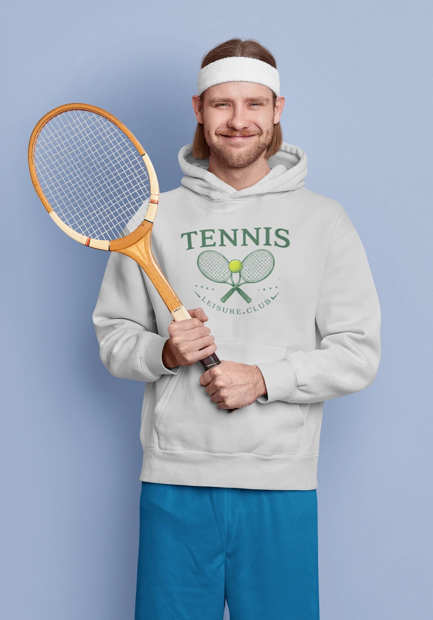 Man wearing a hoodie with a tennis graphic holding a racket against a light blue background