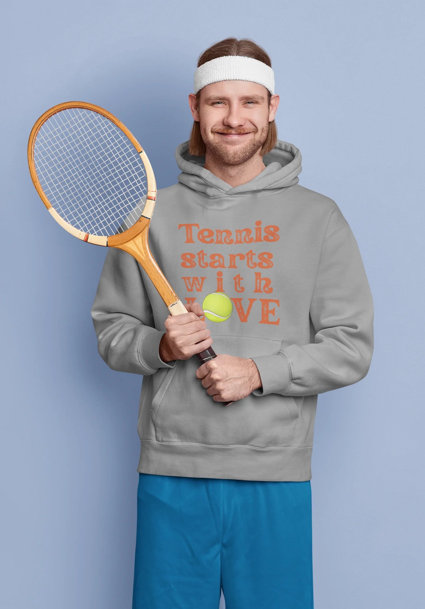 Man holding a tennis racket and ball, wearing a hoodie with 'Tennis starts with LOVE' text on a blue background