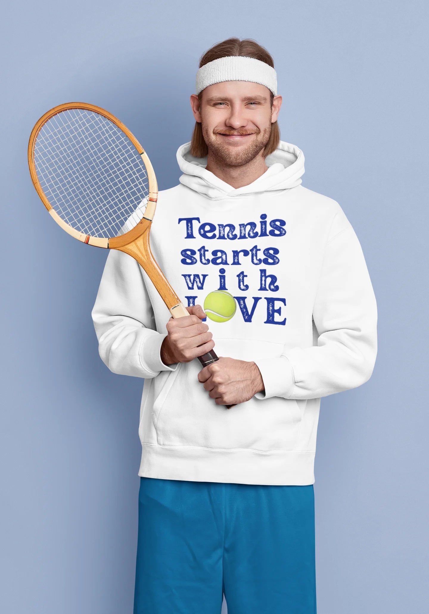 Man holding a tennis racket and wearing a hoodie with 'Tennis starts with LOVE' text on a blue background