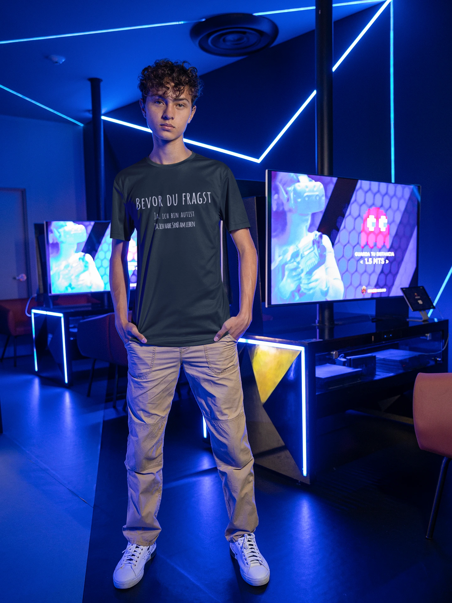 Person wearing a black t-shirt standing in front of multiple monitors in a futuristic room with blue lighting.