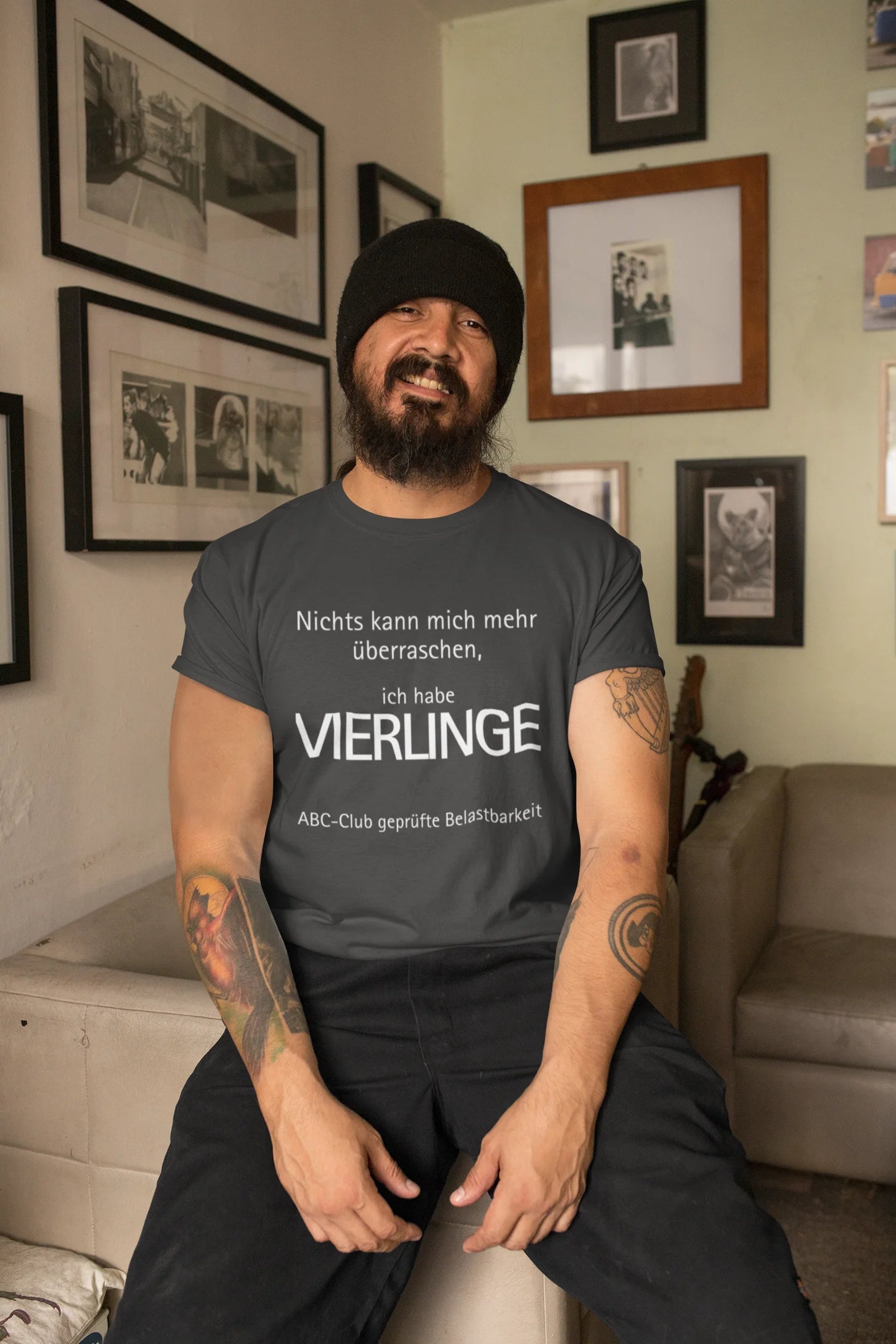 Vierlinge Eltern Shirt Man wearing a gray t-shirt with German text in a living room setting