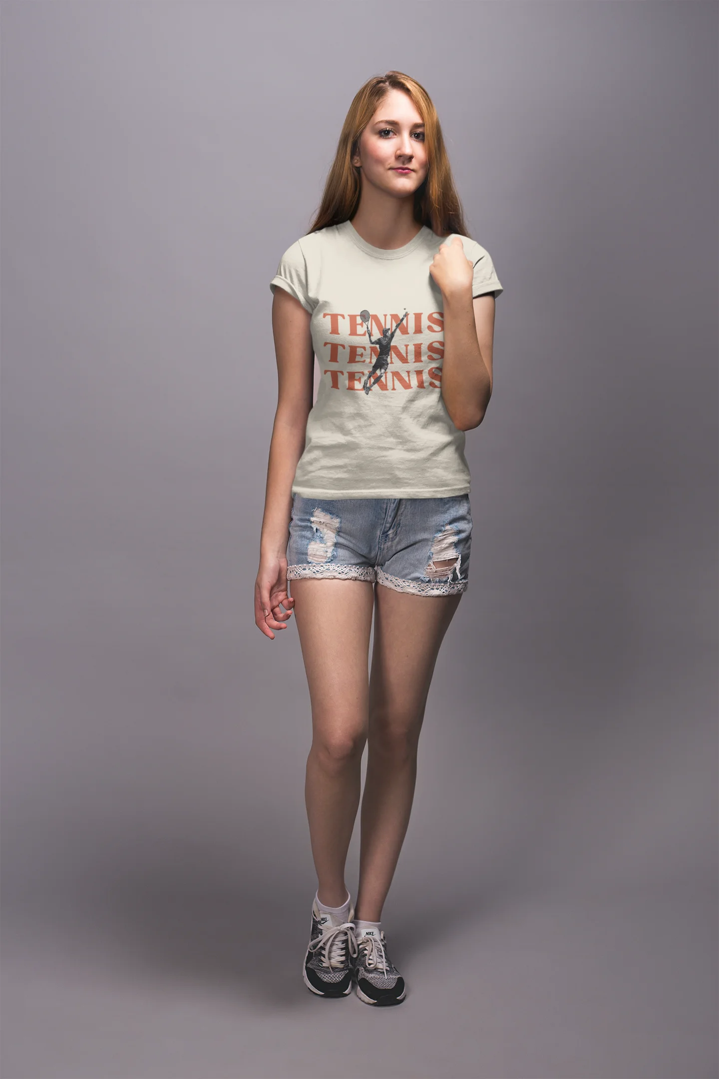 Woman wearing a 'Tennis' t-shirt and denim shorts on a gray background