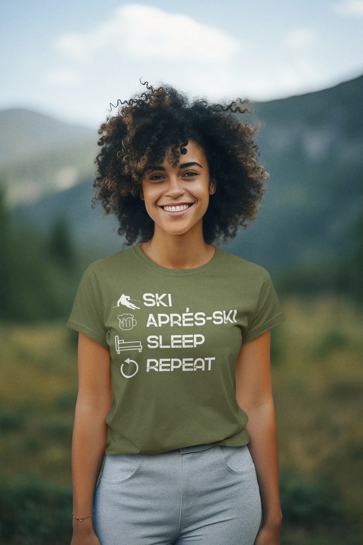 Person wearing a green t-shirt with text in a mountainous landscape